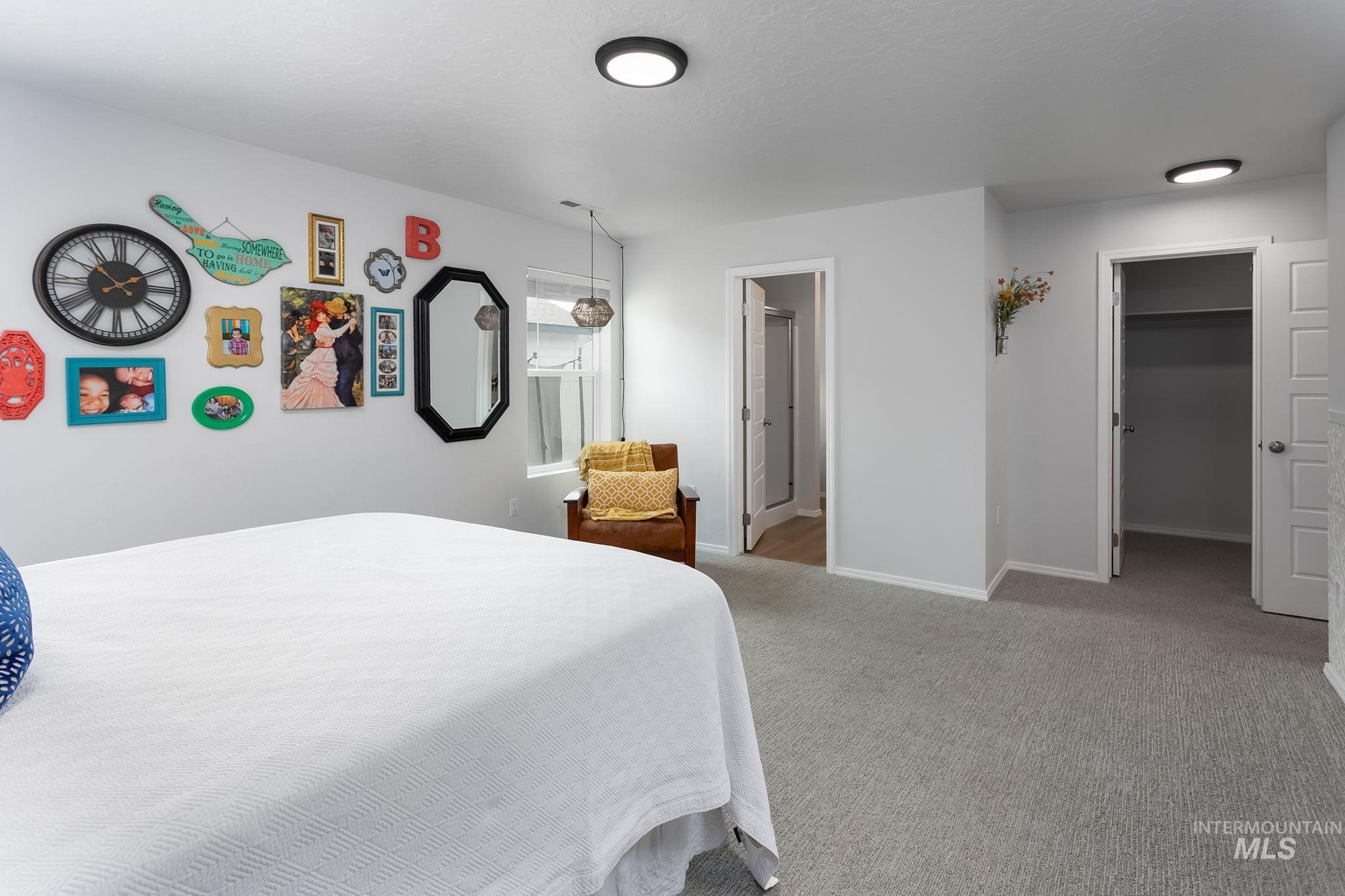 Bedroom with a walk in closet, light colored carpet, and connected bathroom