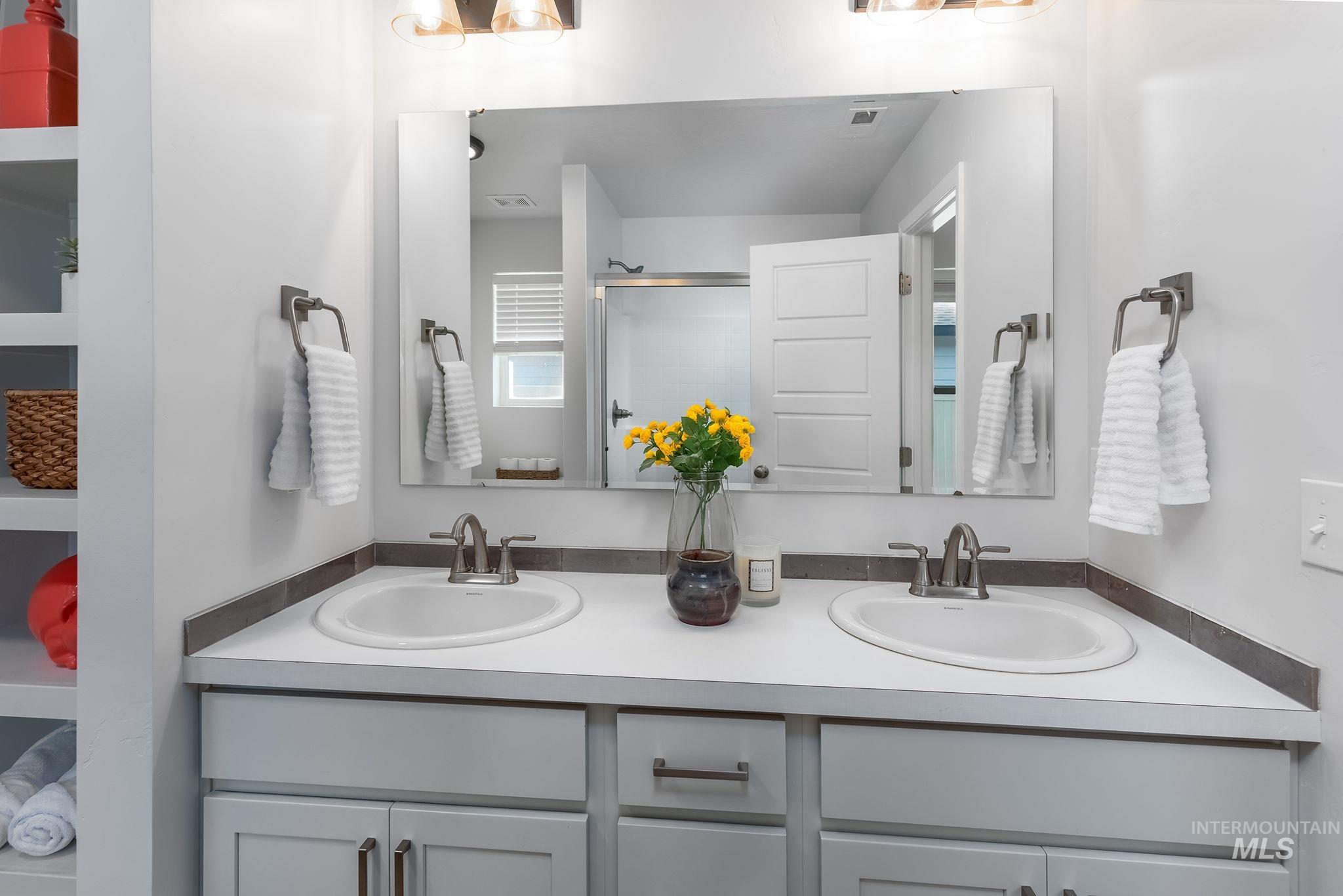 Bathroom featuring a stall shower and double vanity