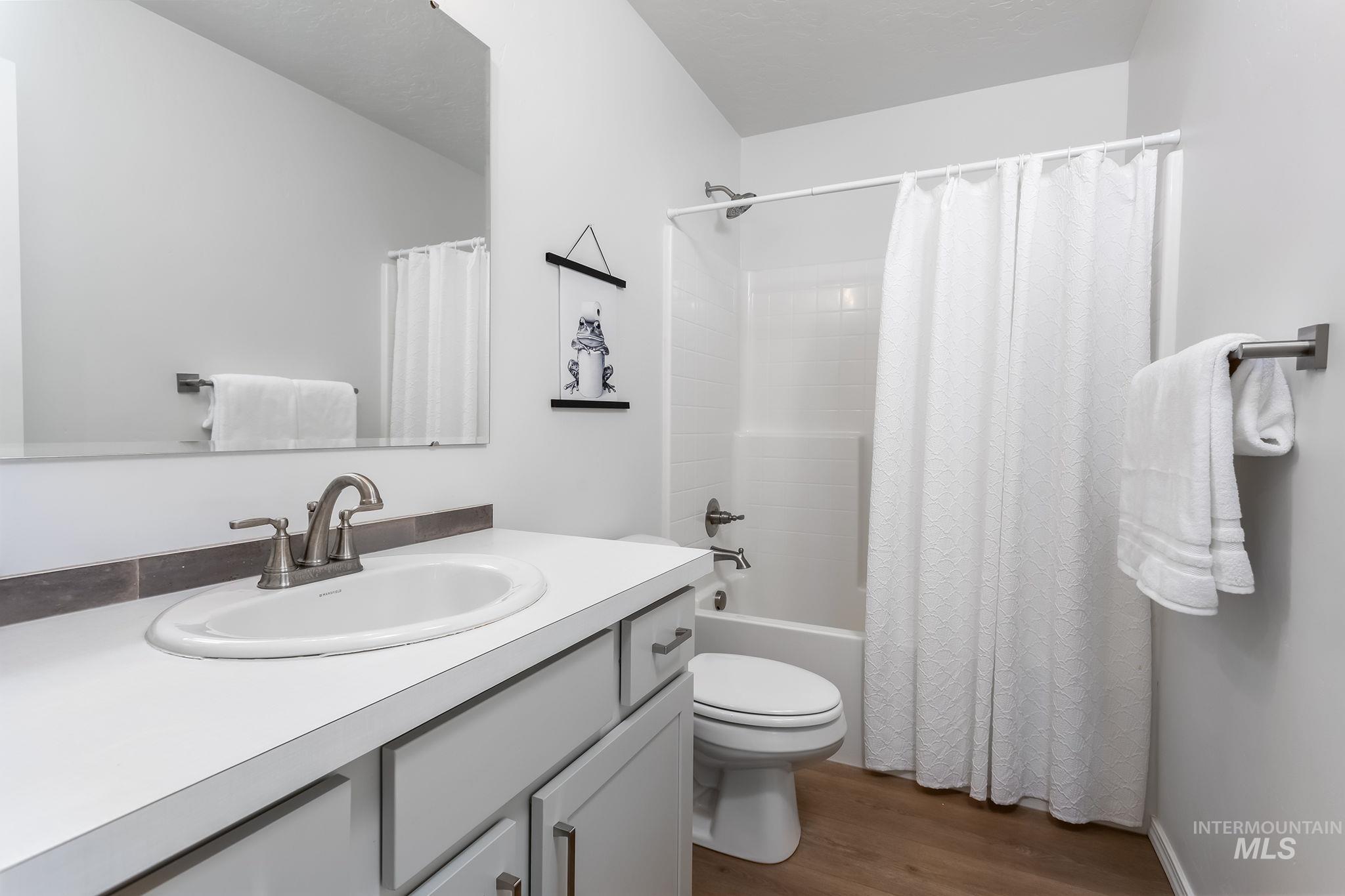 Full bathroom featuring dark wood finished floors, vanity, and shower / bath combo with shower curtain