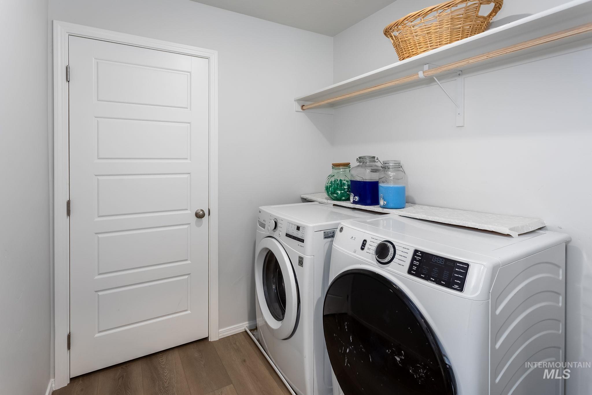 Washroom with dark wood-style flooring and washing machine and dryer
