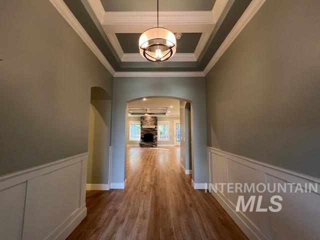 Corridor featuring a decorative wall, a wainscoted wall, arched walkways, dark wood finished floors, and a chandelier