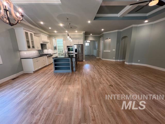 Kitchen with dark countertops, pendant lighting, open shelves, glass insert cabinets, and open floor plan