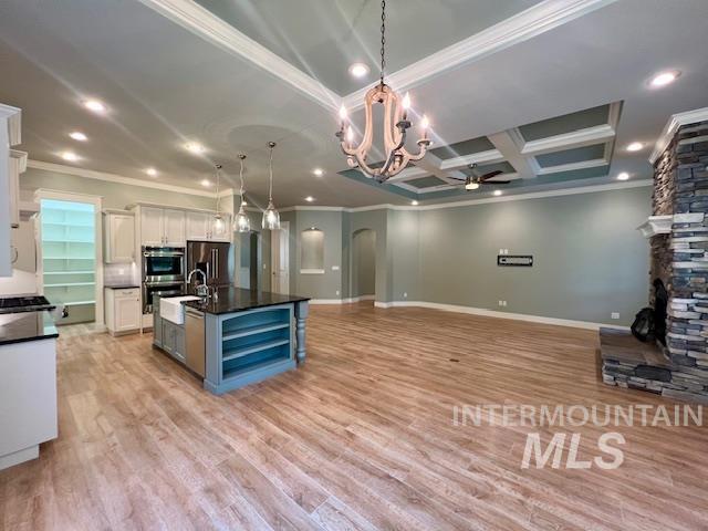 Kitchen featuring ornamental molding, decorative light fixtures, open floor plan, open shelves, and arched walkways