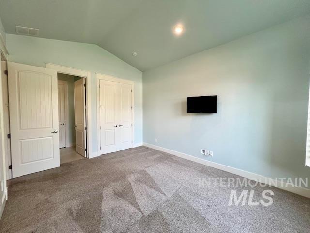 Unfurnished bedroom with vaulted ceiling, carpet flooring, and a closet