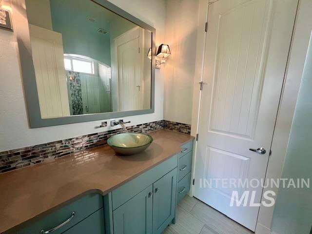Bathroom featuring vanity and decorative backsplash