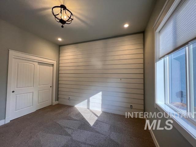 Spare room with carpet, wood walls, and recessed lighting