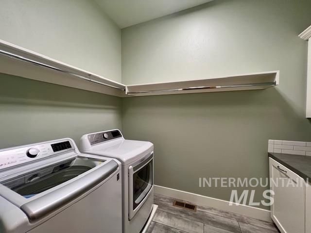 Laundry area with washing machine and dryer, cabinet space, and dark wood-type flooring