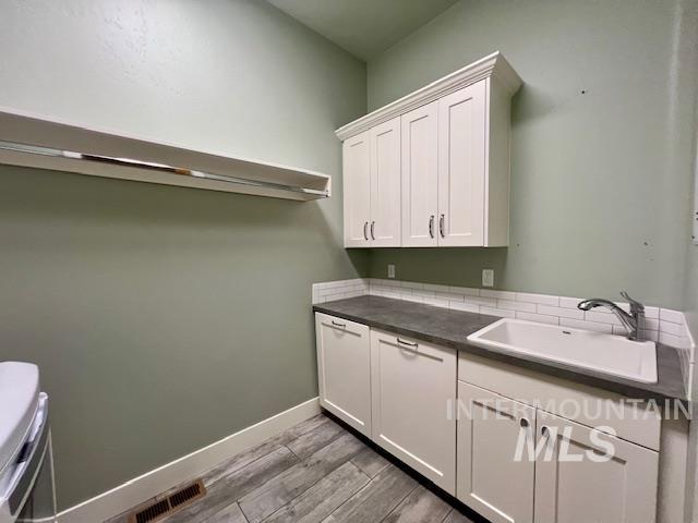 Laundry room featuring baseboards and dark wood-style floors