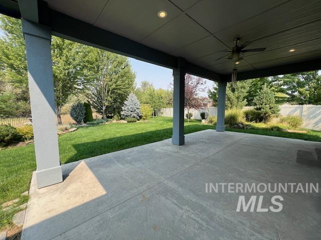 Fenced backyard with a ceiling fan and a patio