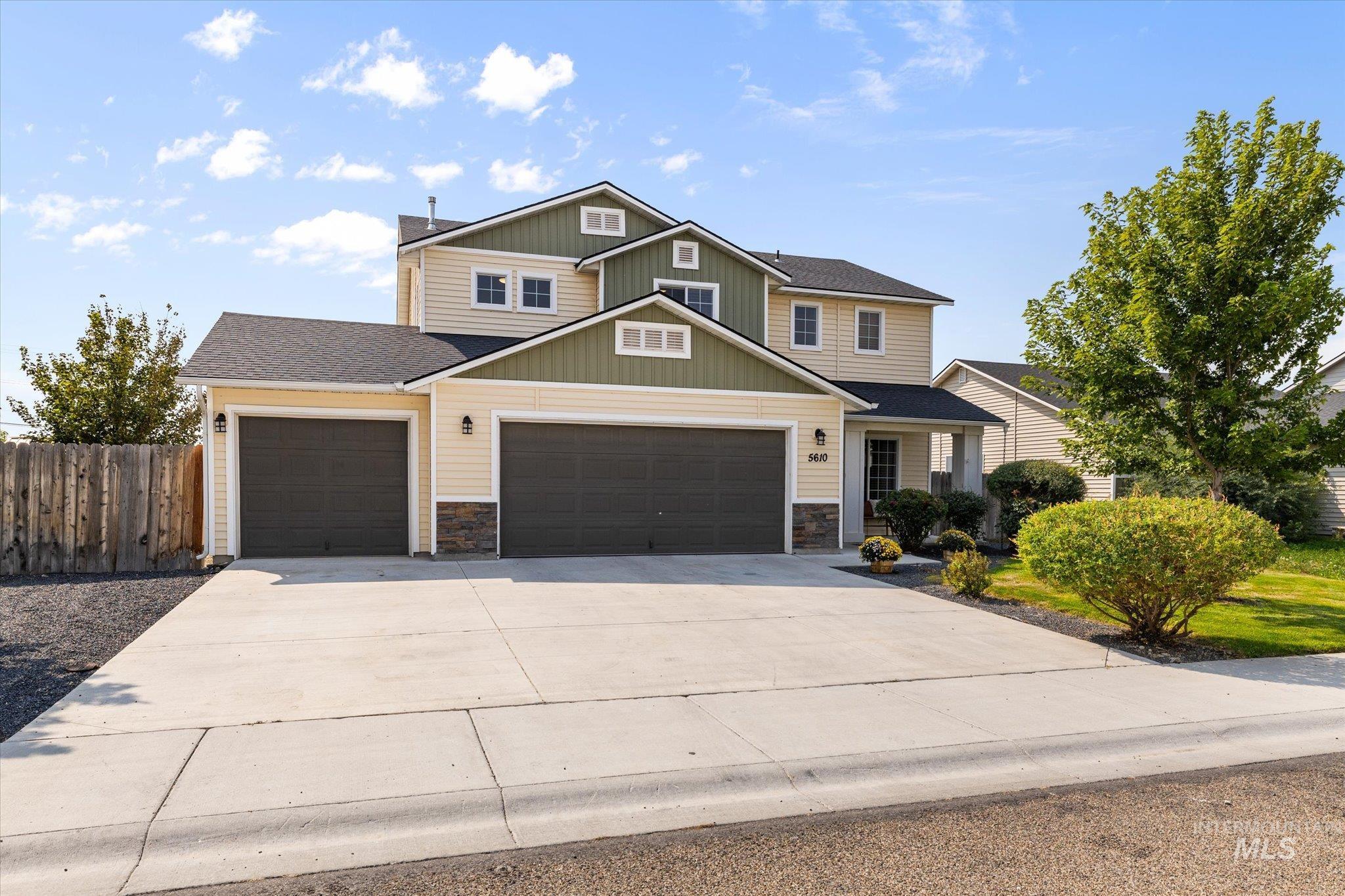 View of front of house with concrete driveway, a garage, a shingled roof, and stone siding