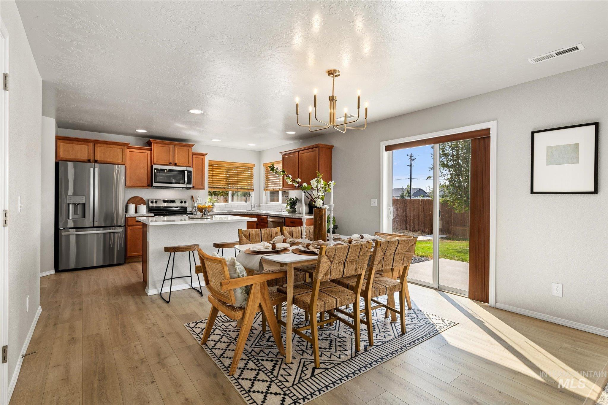 Dining room with light wood finished floors, recessed lighting, a chandelier, and a textured ceiling