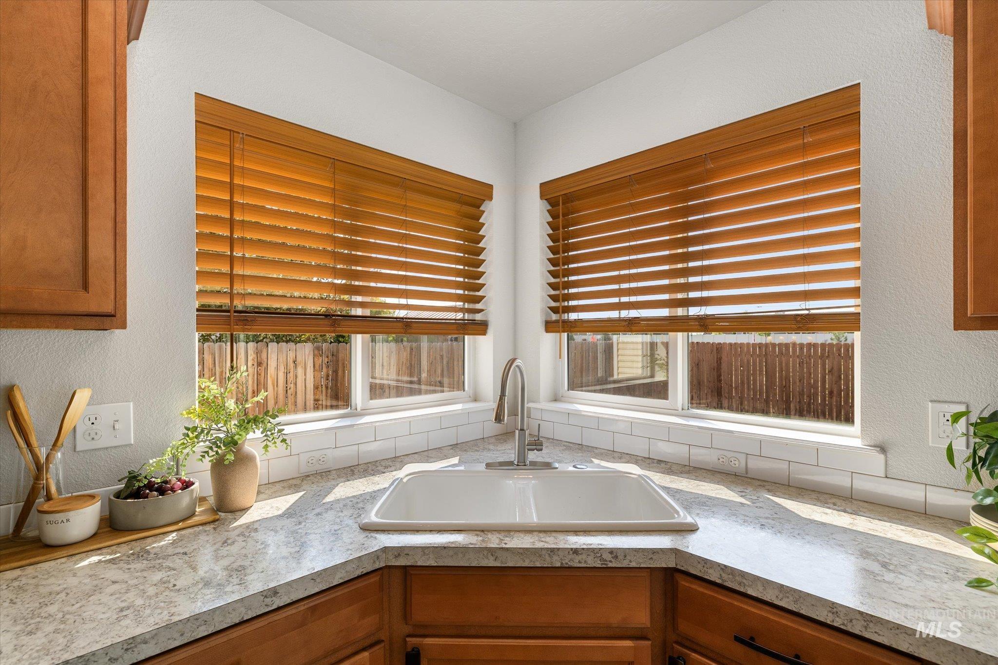 Kitchen with a textured wall, brown cabinets, and light countertops