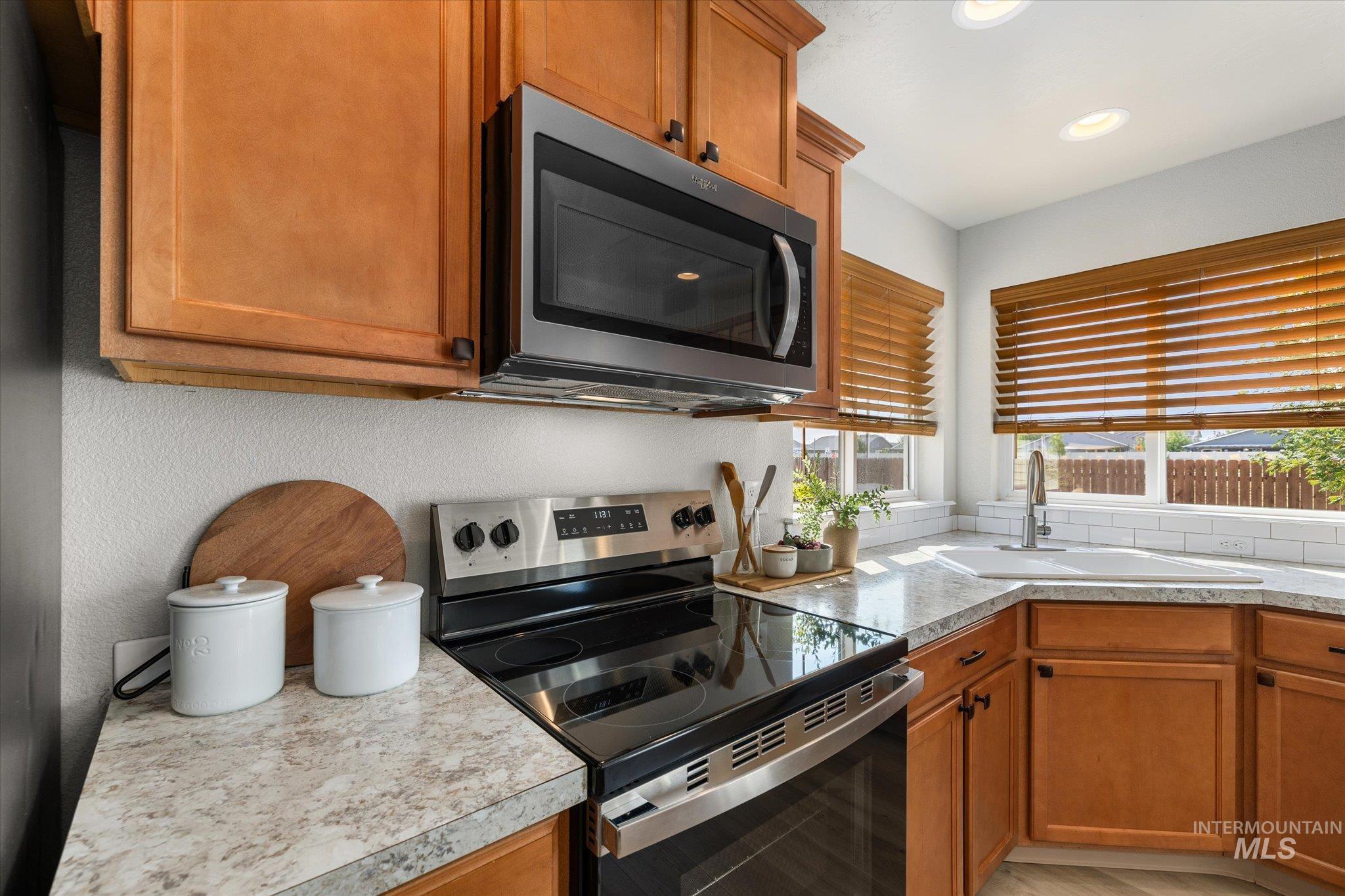 Kitchen featuring appliances with stainless steel finishes, brown cabinets, light countertops, and recessed lighting