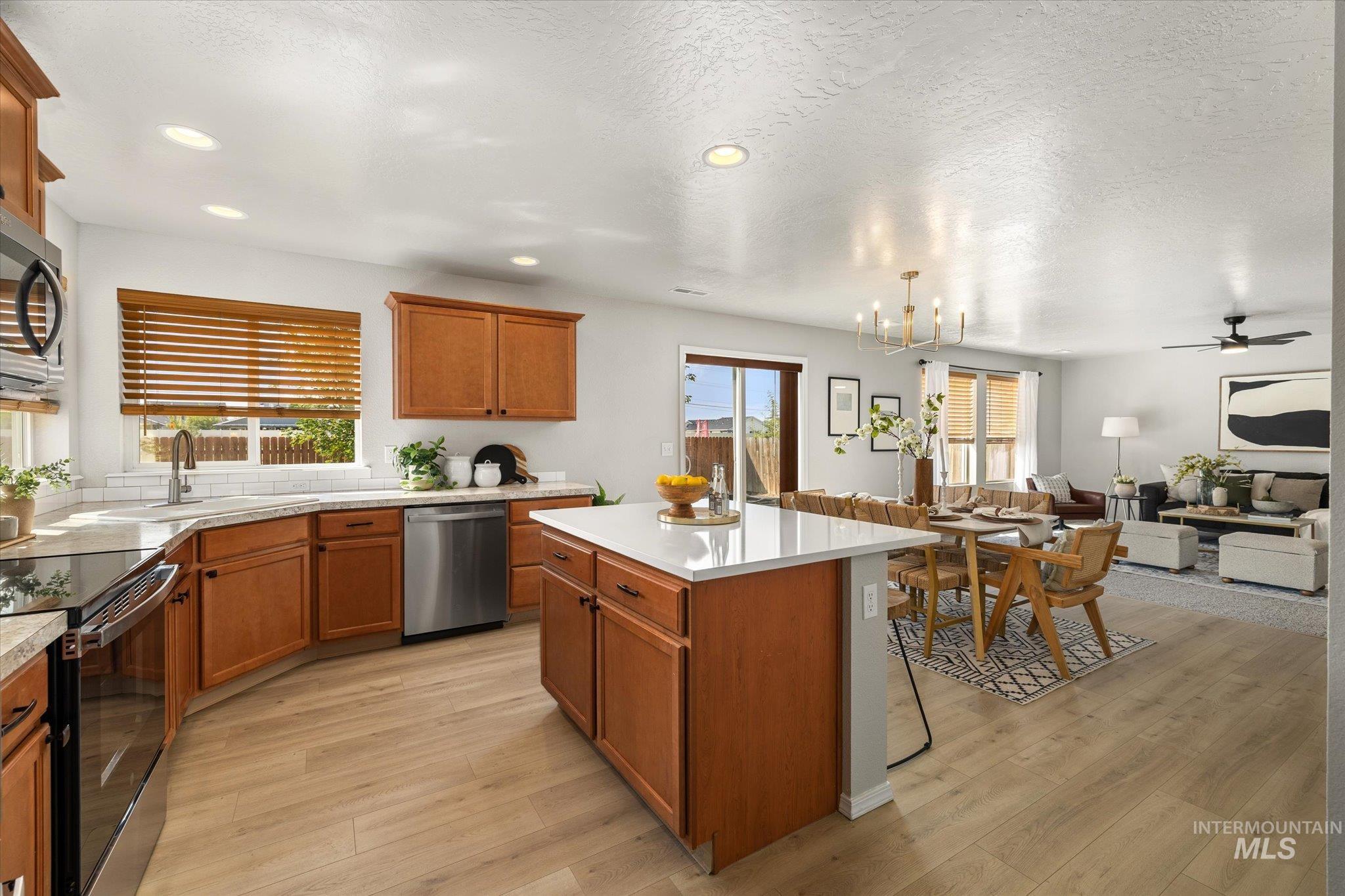 Kitchen with brown cabinets, a center island, stainless steel appliances, a breakfast bar, and light wood-type flooring