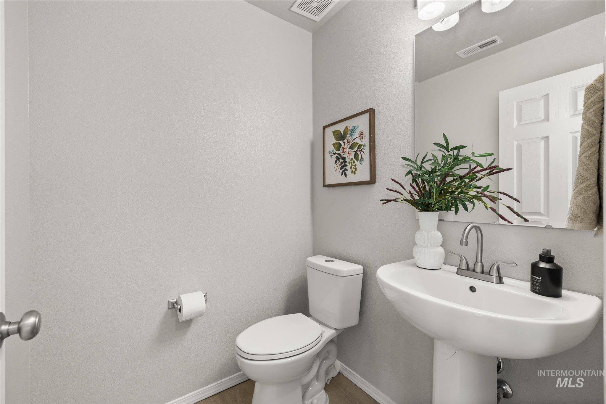 Half bath featuring a textured wall and wood finished floors