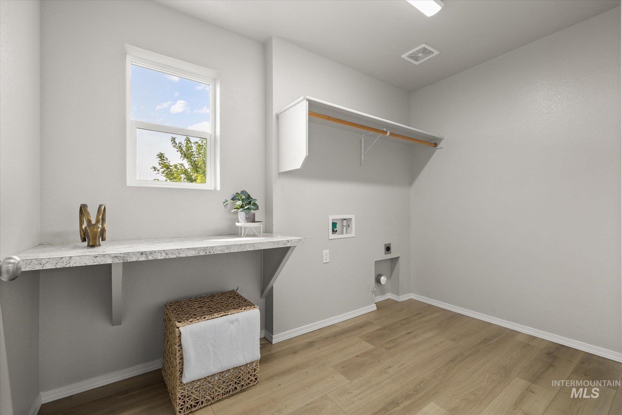 Laundry room with hookup for an electric dryer, light wood-style flooring, and washer hookup