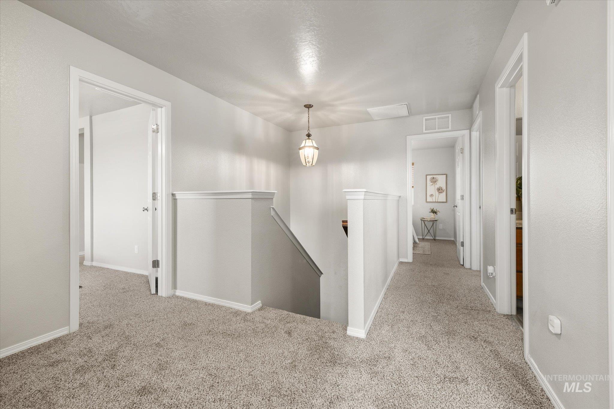 Hall featuring an upstairs landing and light colored carpet