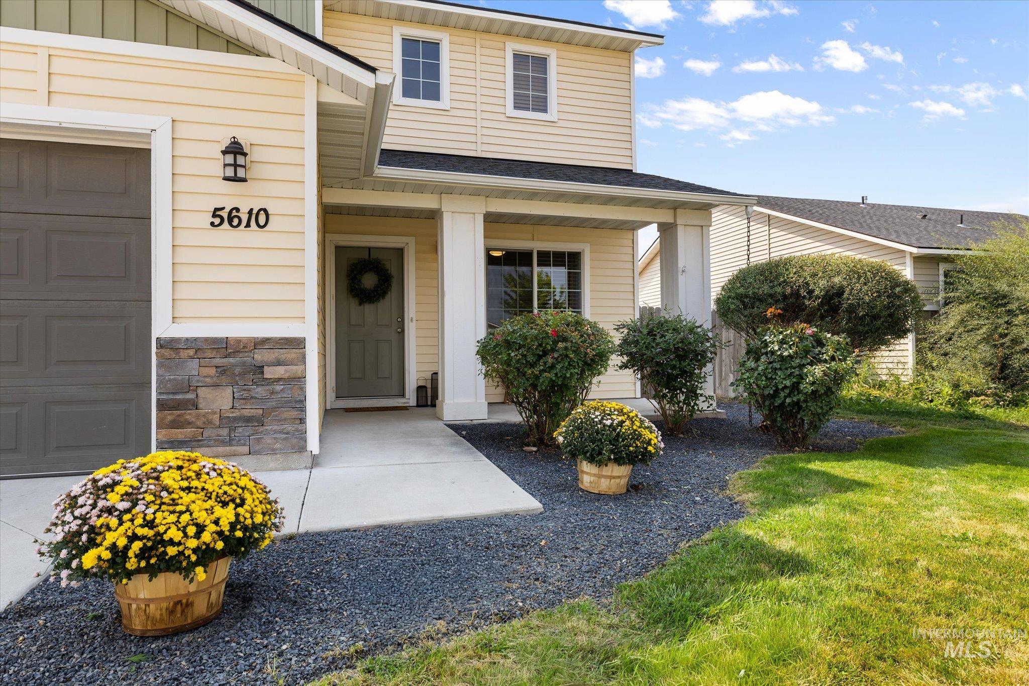 View of exterior entry with a garage, stone siding, covered porch, and board and batten siding