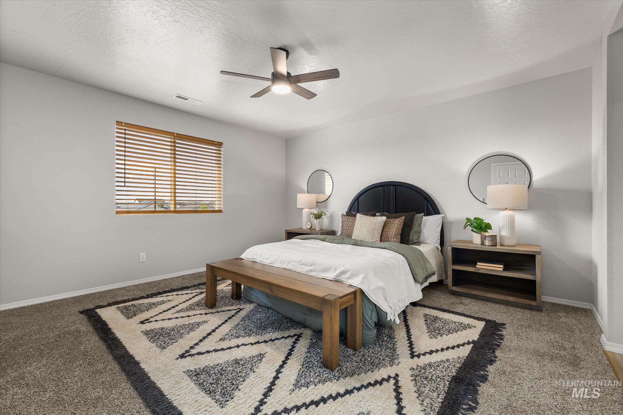 Carpeted bedroom featuring a textured ceiling and a ceiling fan