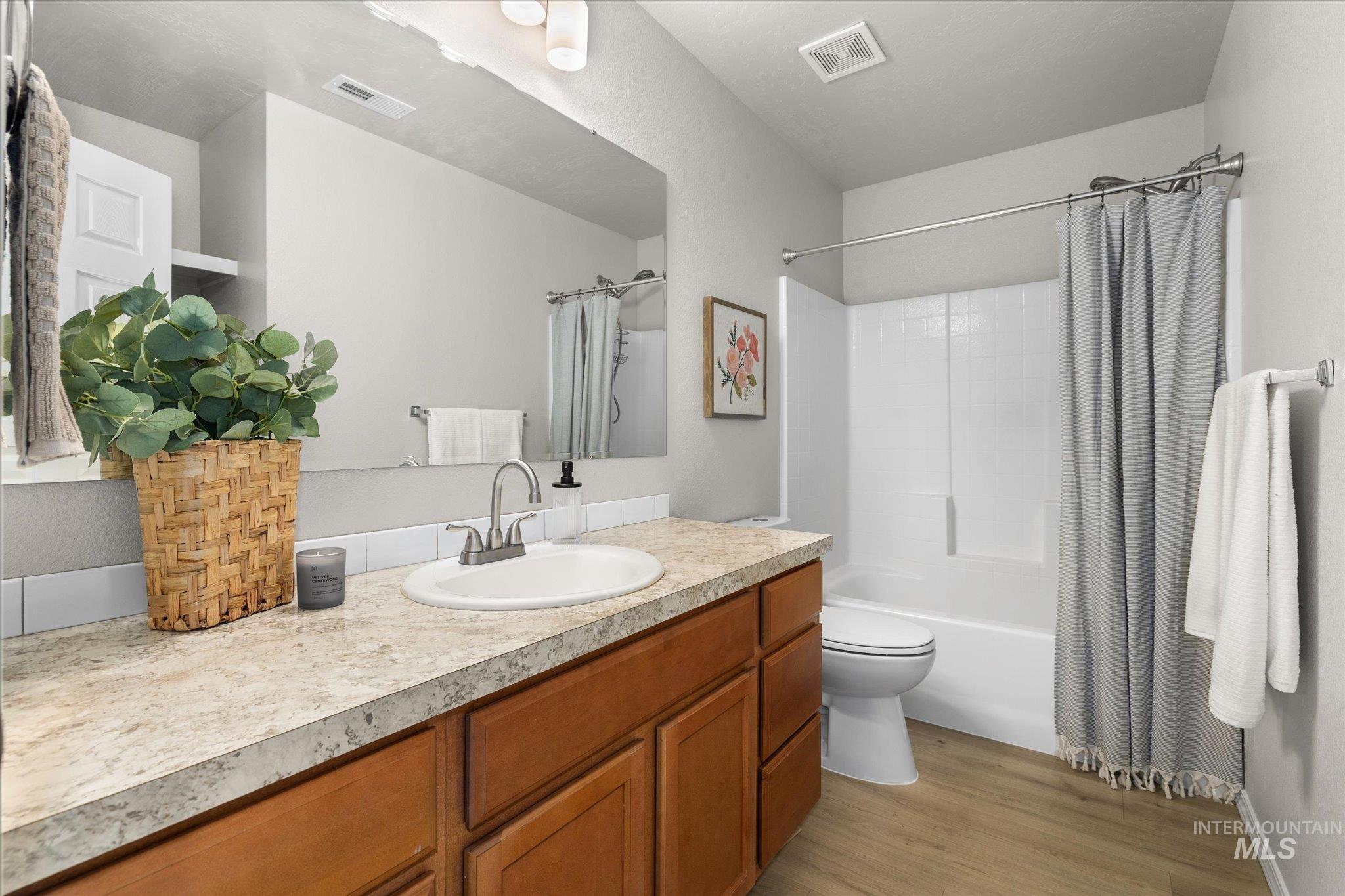 Full bathroom featuring shower / bath combo, vanity, and light wood-style floors