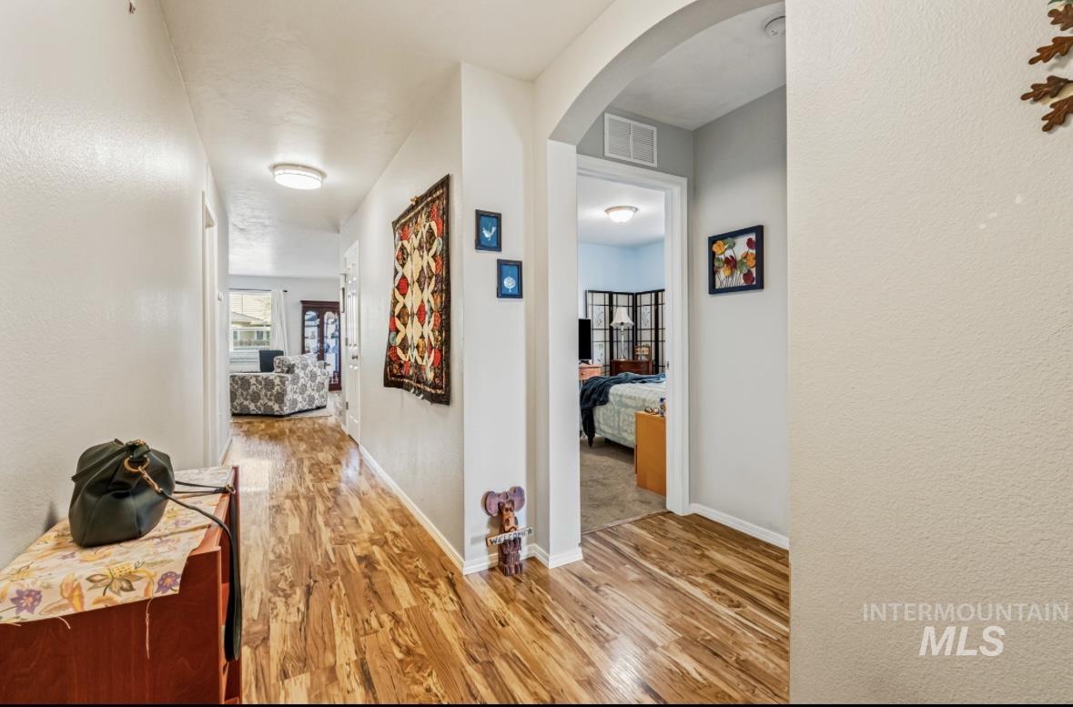 Corridor featuring arched walkways, light wood finished floors, and a textured wall