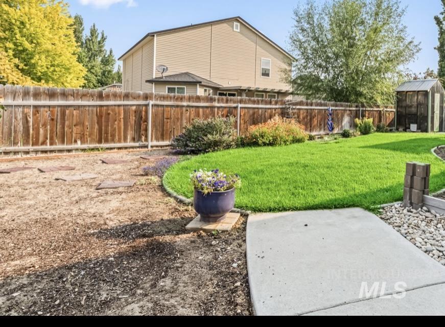 Fenced backyard featuring a storage unit and a patio