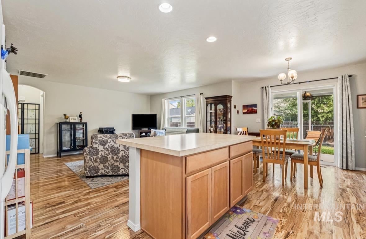 Kitchen featuring light countertops, open floor plan, light wood-style floors, a kitchen island, and arched walkways