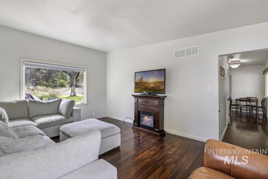 Living room featuring dark wood-style floors and a glass covered fireplace