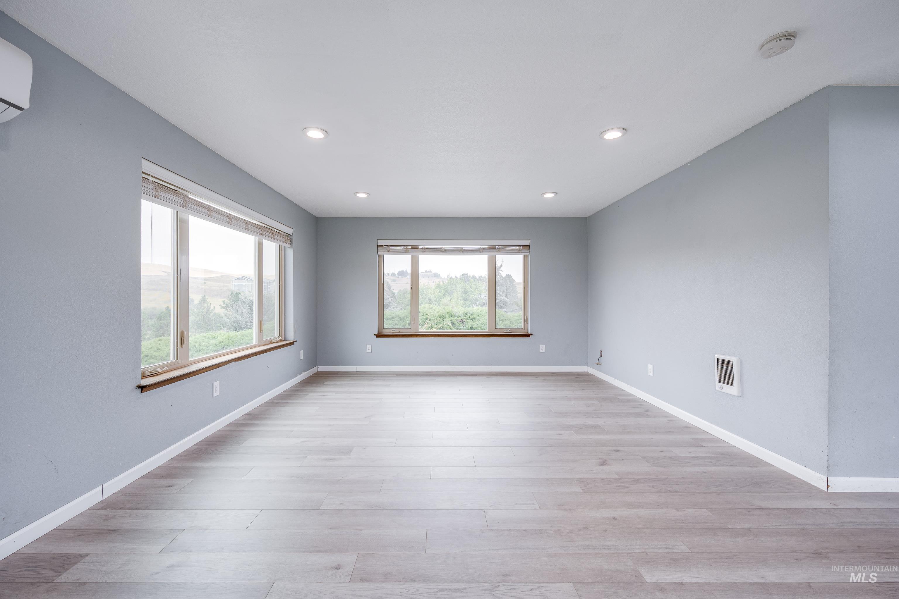 Spare room with plenty of natural light, light wood-style floors, recessed lighting, and a wall unit AC