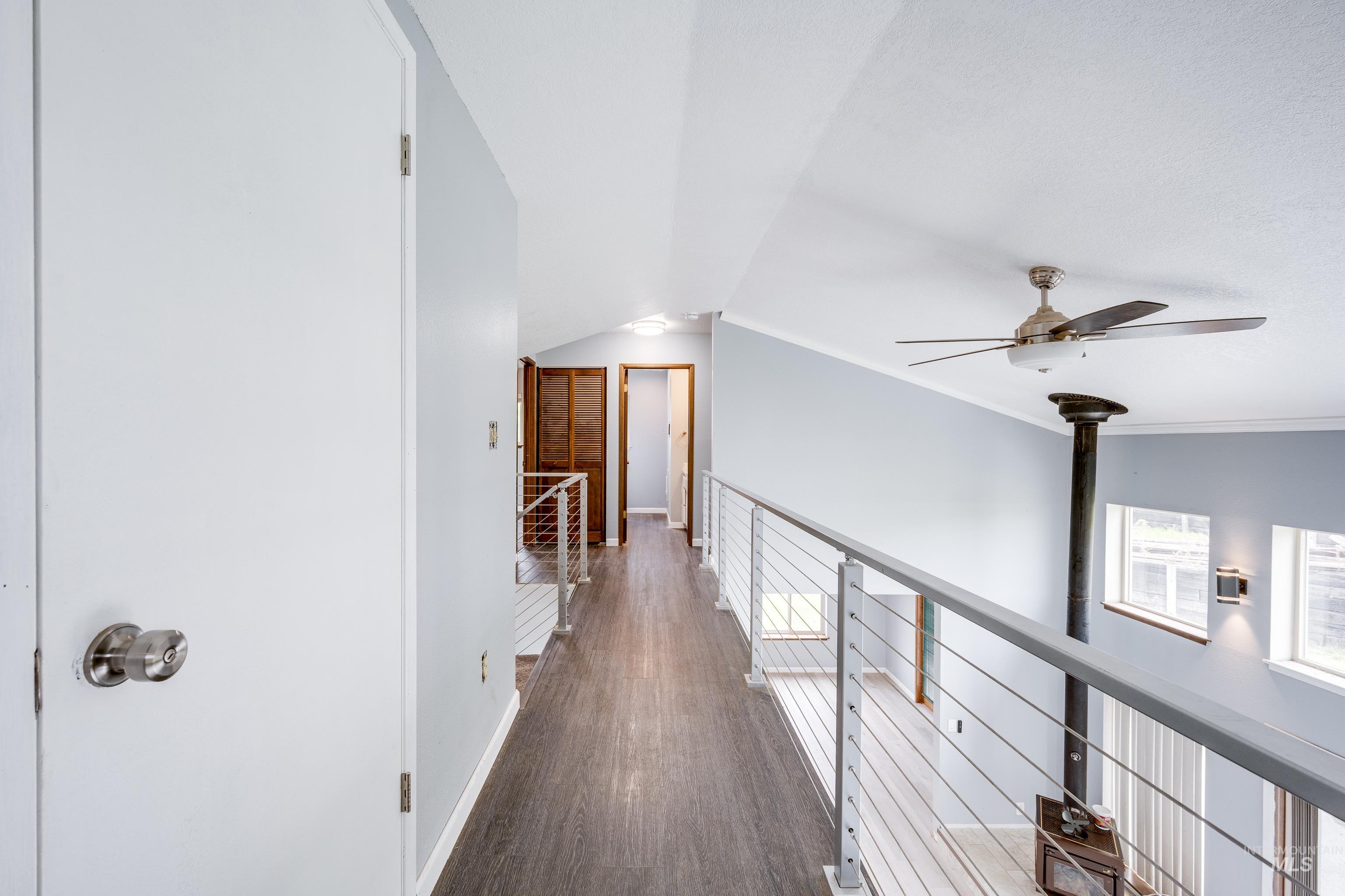 Hallway featuring dark wood-type flooring, vaulted ceiling, and an upstairs landing