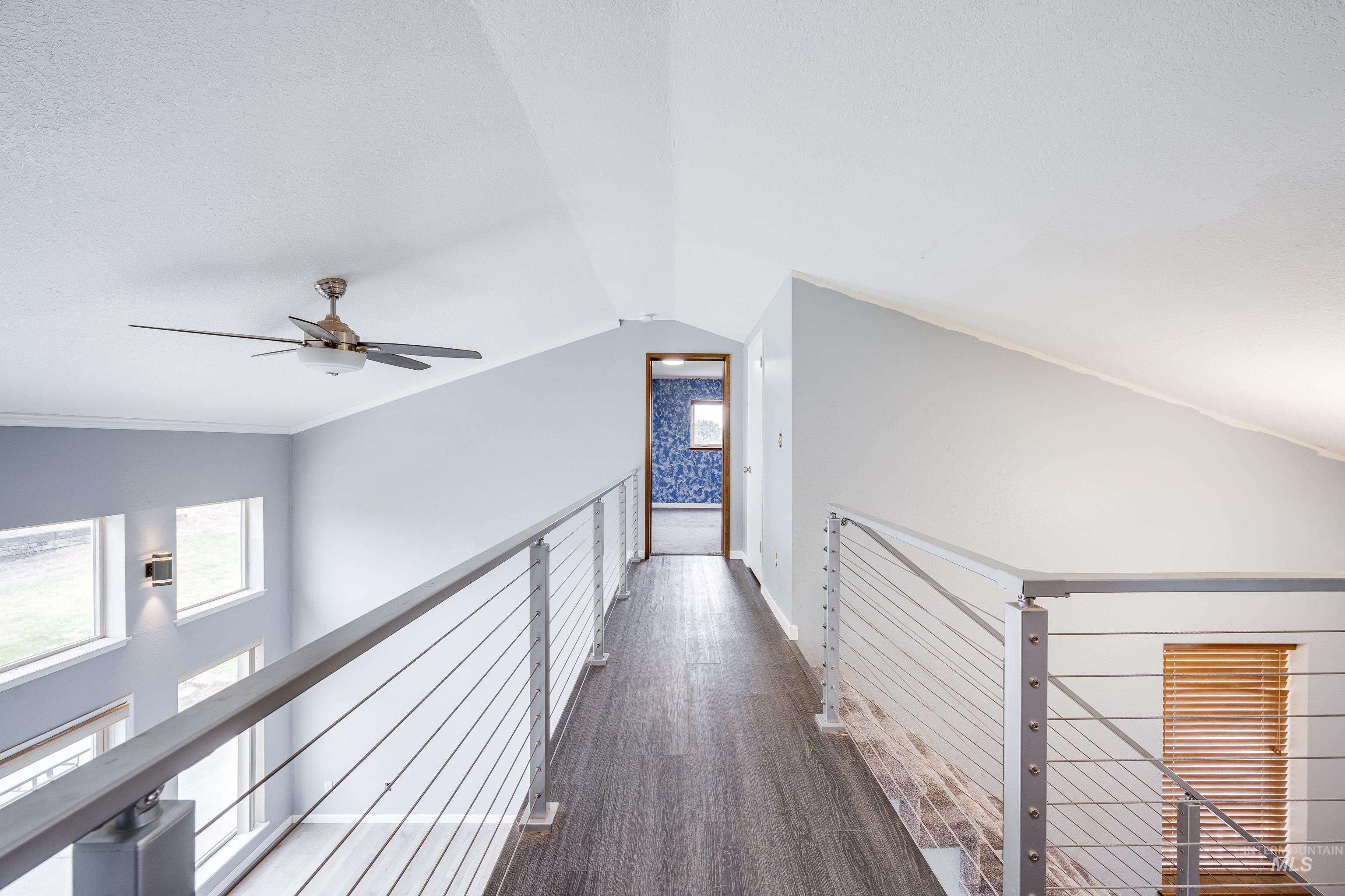 Hallway with lofted ceiling, dark wood-type flooring, and an upstairs landing