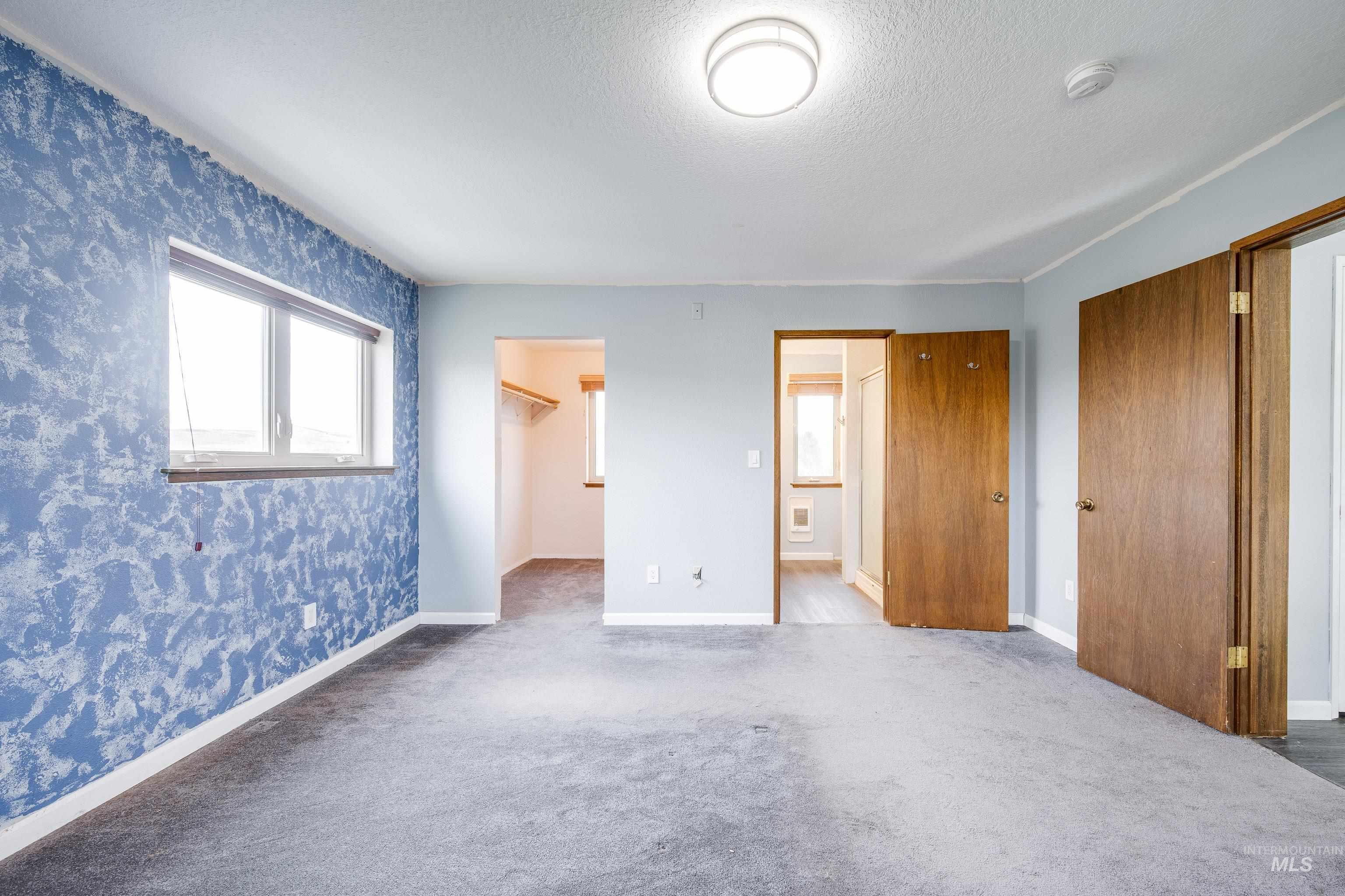Unfurnished bedroom with a walk in closet, carpet, a textured ceiling, and ensuite bathroom