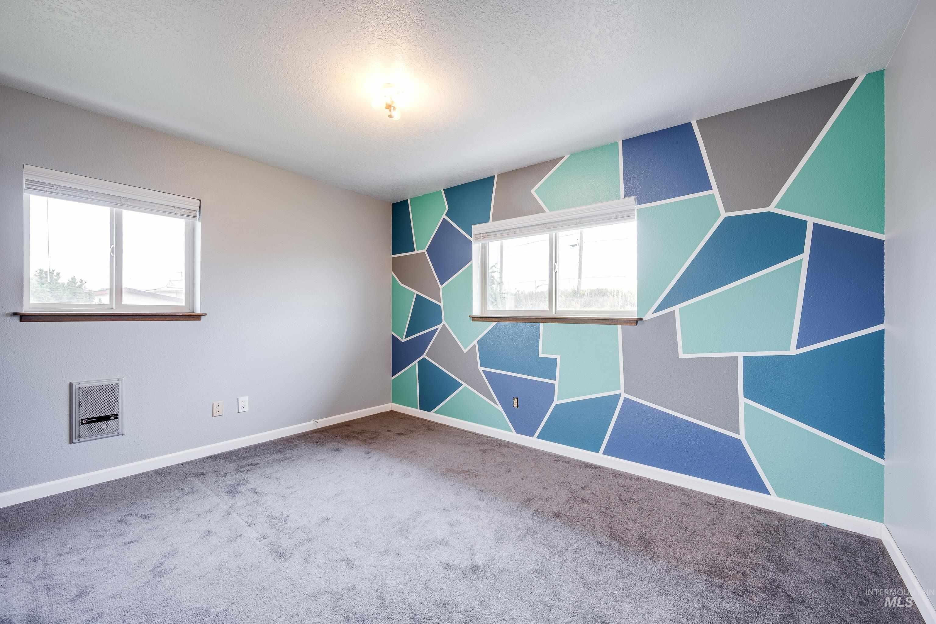 Spare room with an accent wall, carpet, heating unit, and a textured ceiling