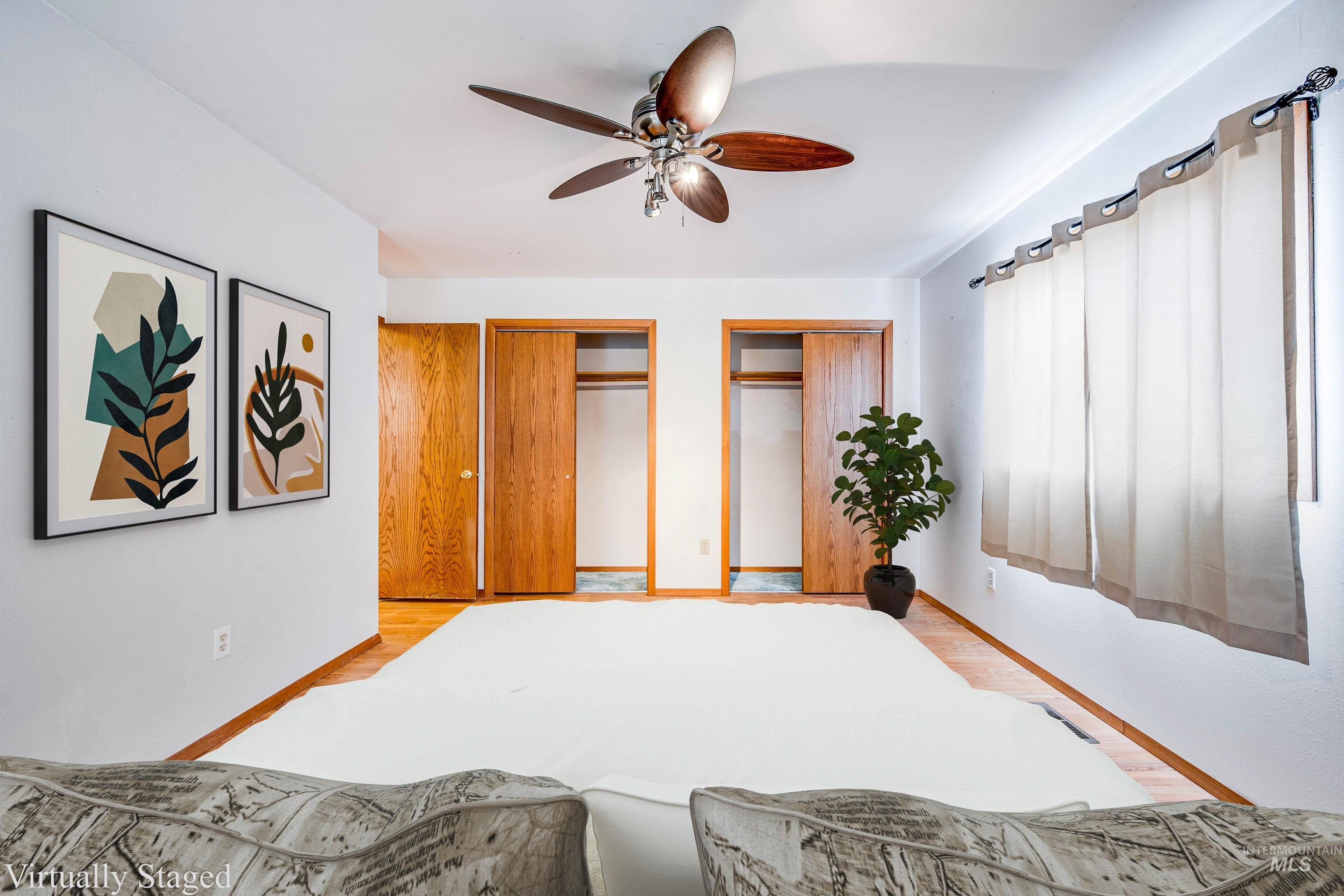 Bedroom with multiple closets, wood finished floors, and a ceiling fan