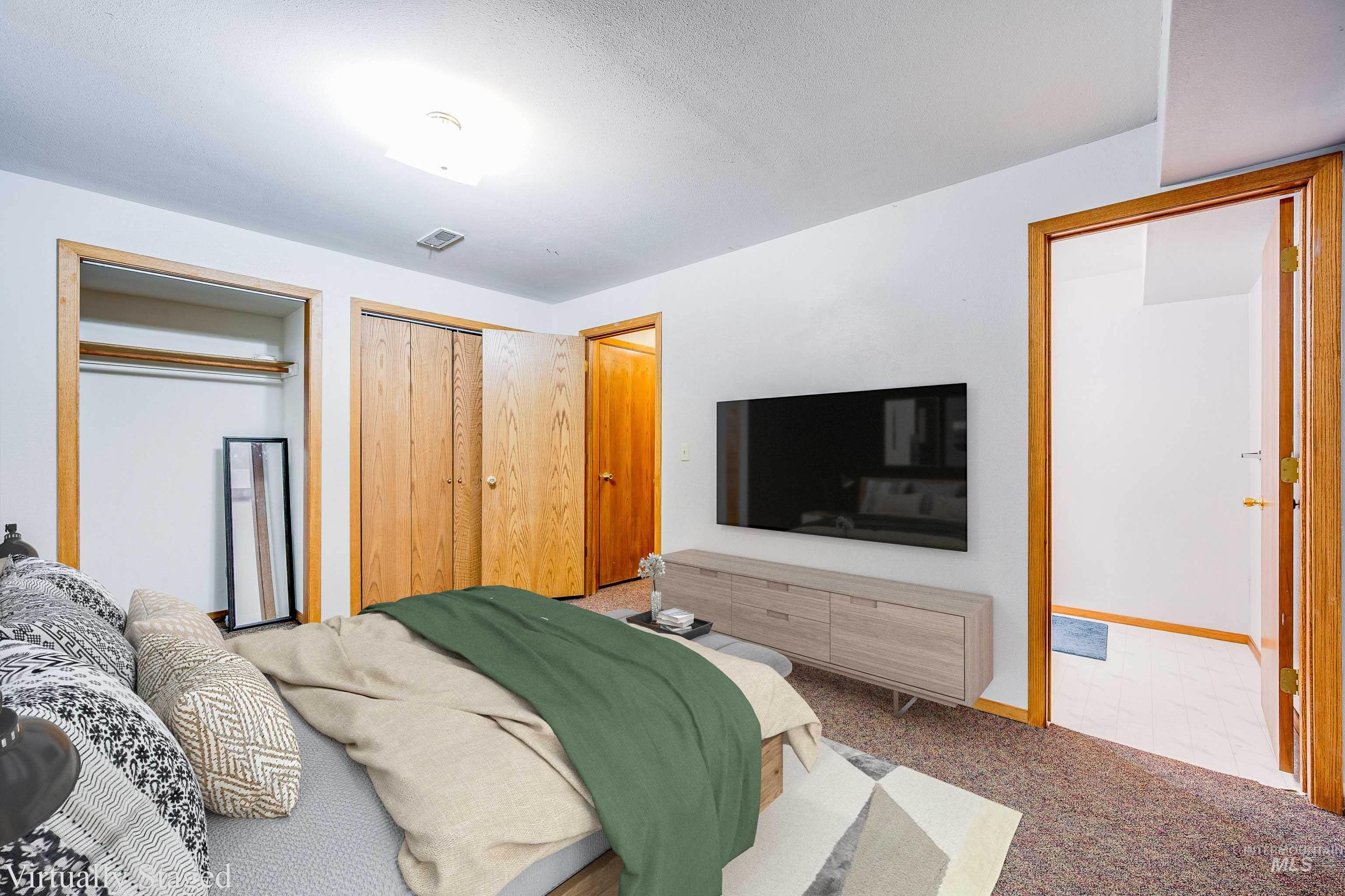 Carpeted bedroom featuring multiple closets and baseboards