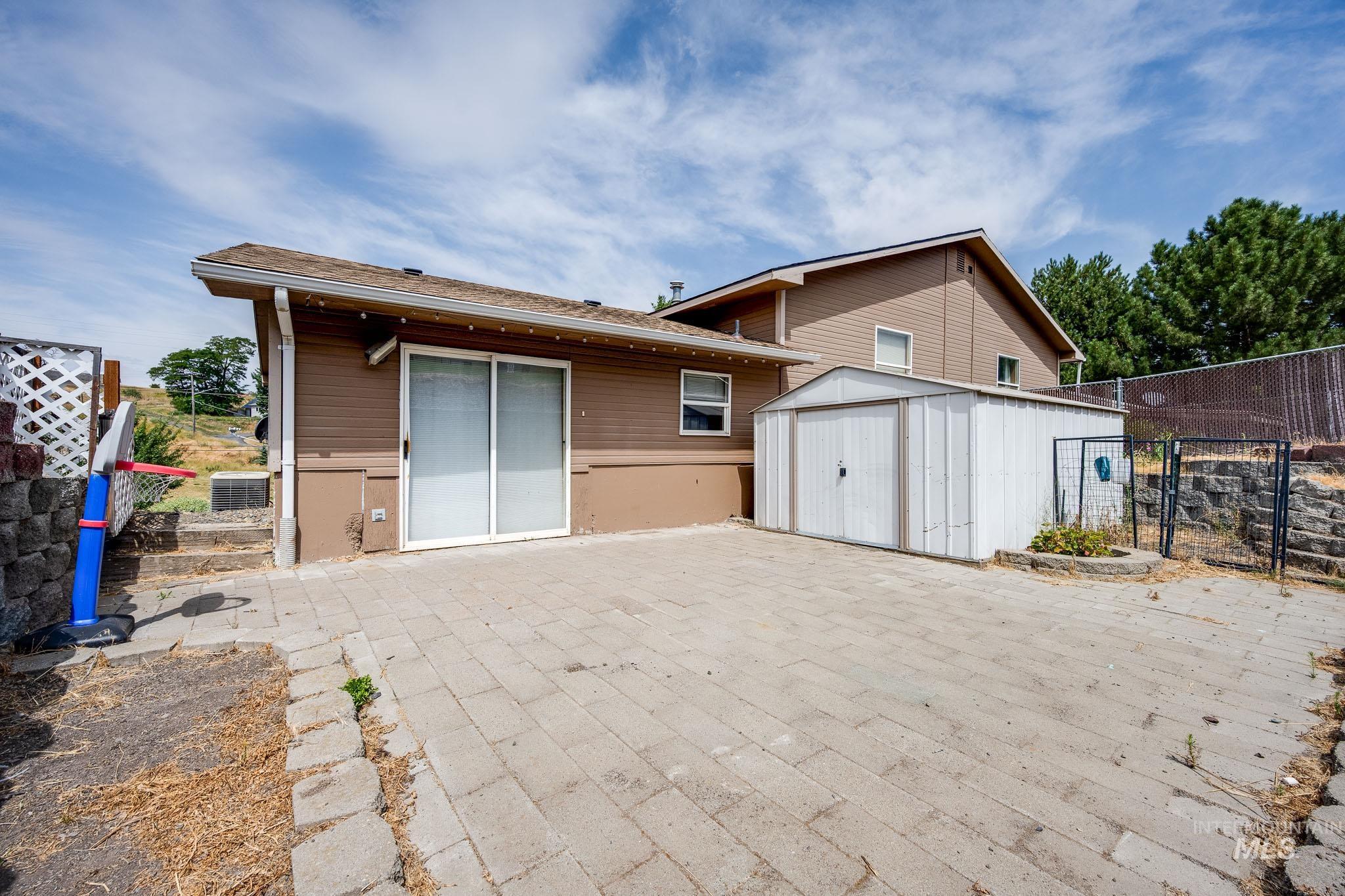 Back of property with a shed and a shingled roof