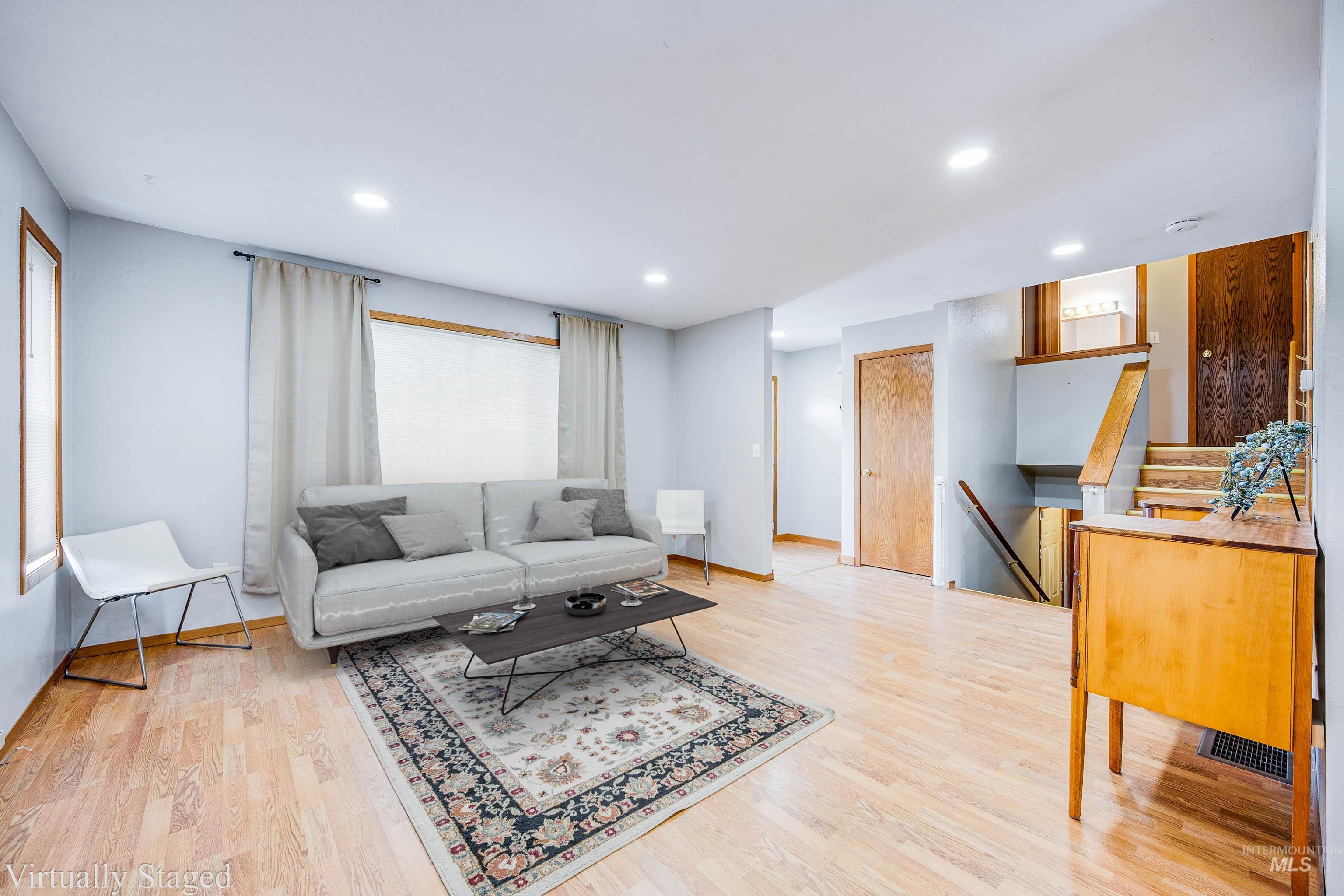 Living room featuring light wood finished floors, recessed lighting, and stairs
