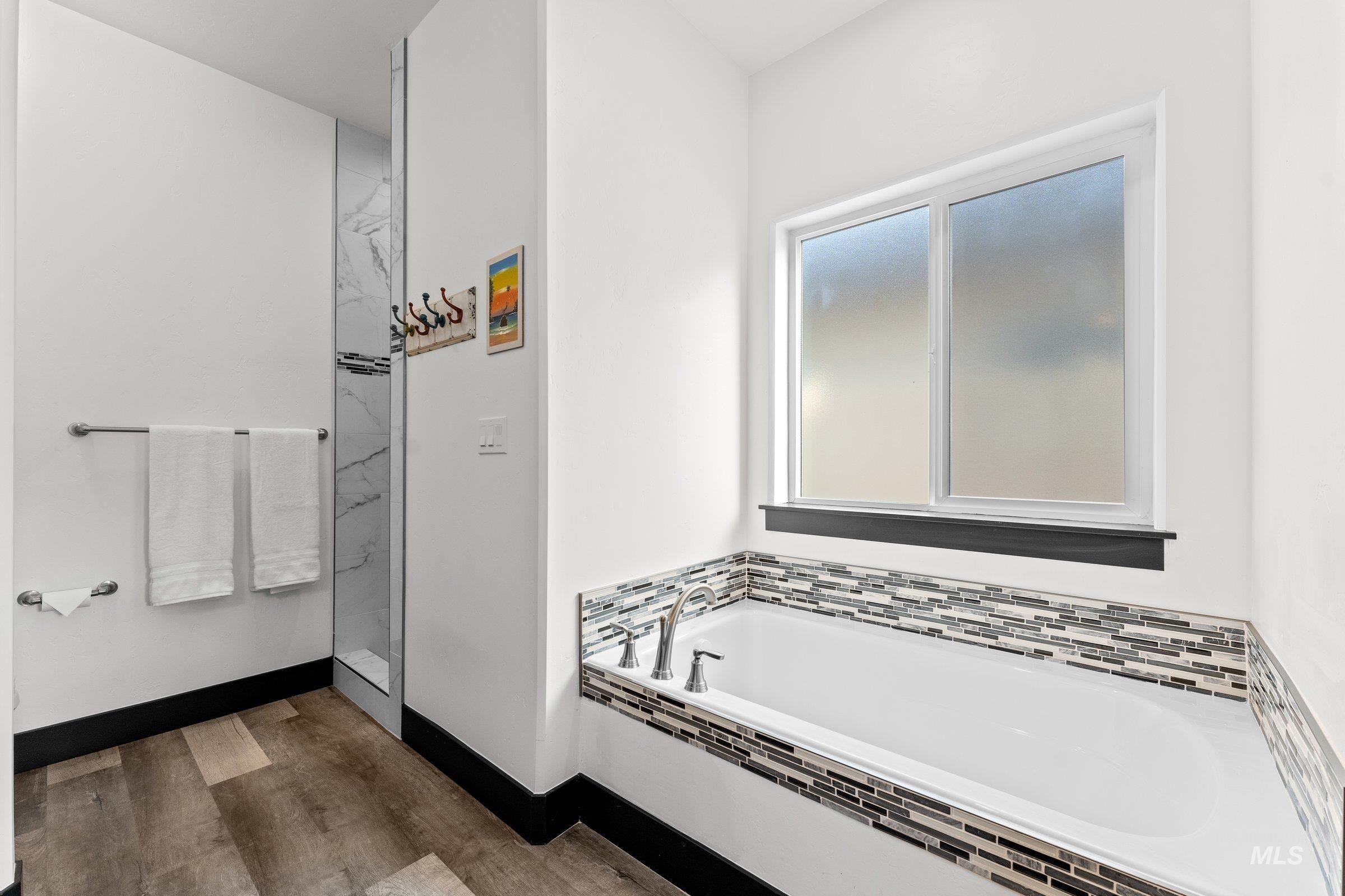 Full bath featuring a bath and dark wood-type flooring