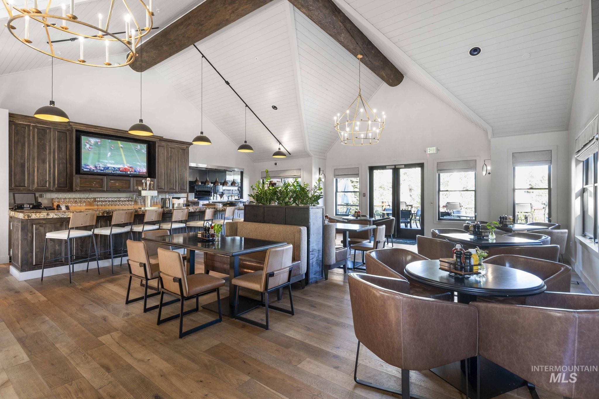 Dining room featuring a chandelier, high vaulted ceiling, beam ceiling, dark wood-type flooring, and french doors