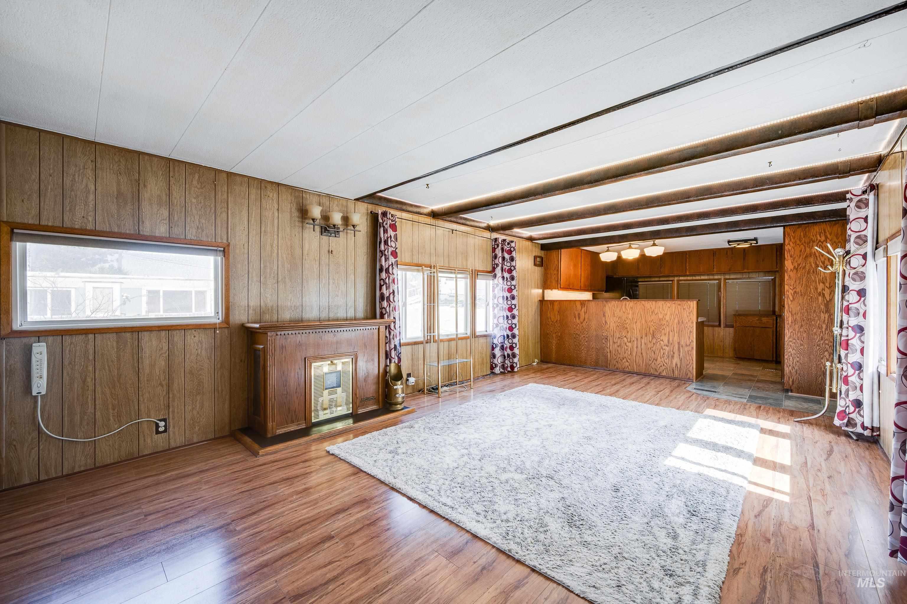 Unfurnished living room featuring wooden walls and light wood finished floors