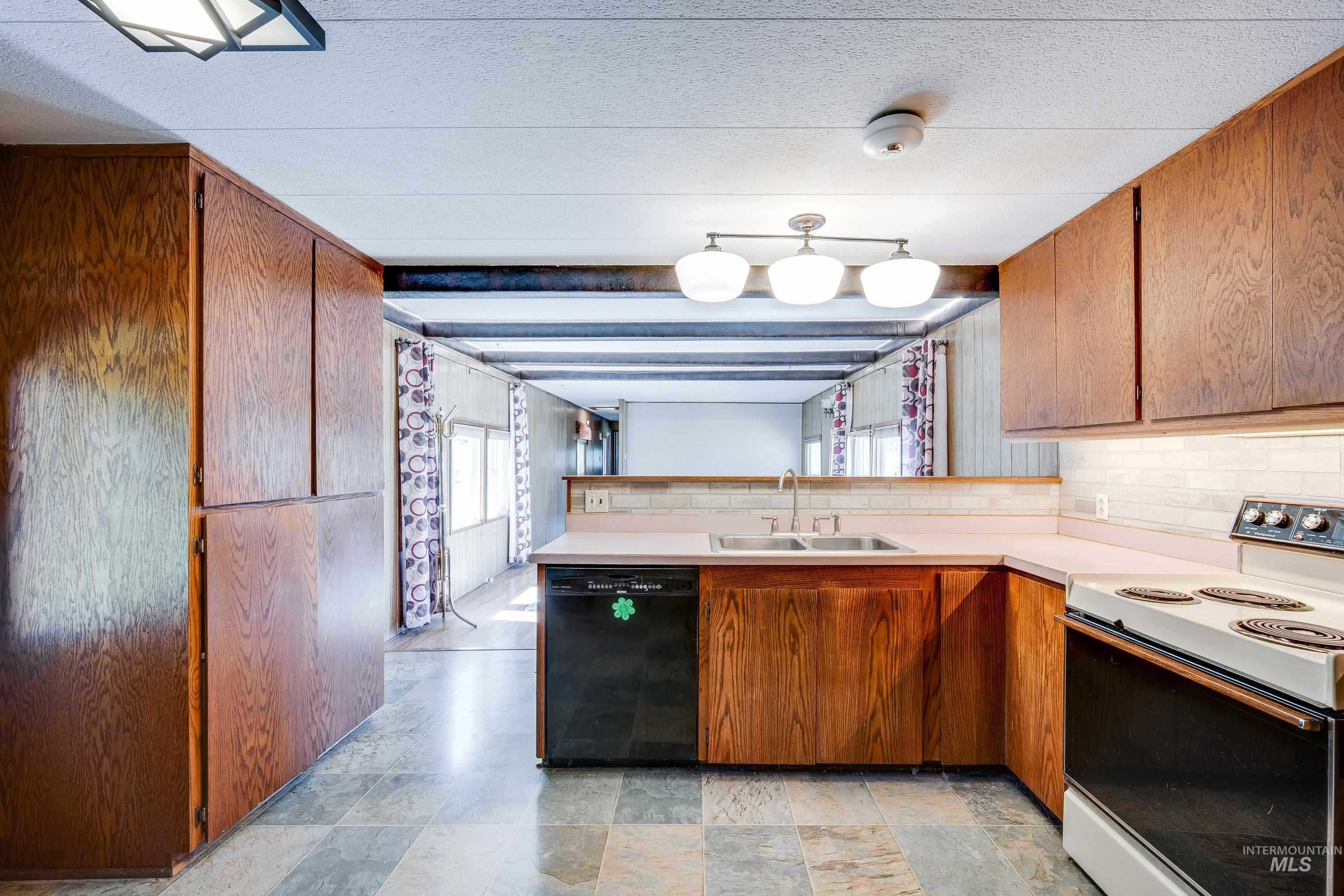 Kitchen featuring electric stove, a peninsula, dishwasher, light countertops, and brown cabinets