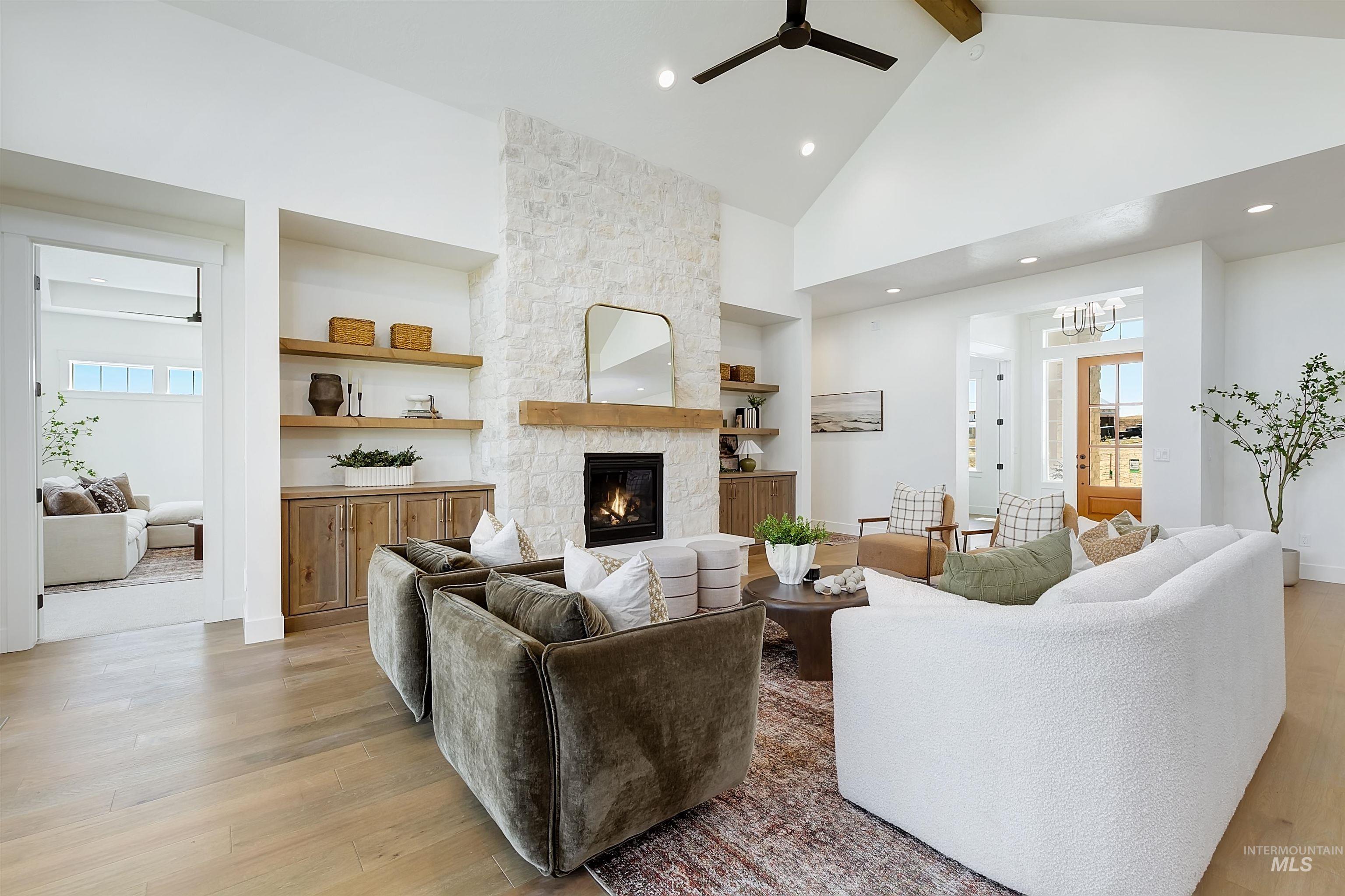 Living area with high vaulted ceiling, beam ceiling, light wood finished floors, a fireplace, and built in shelves