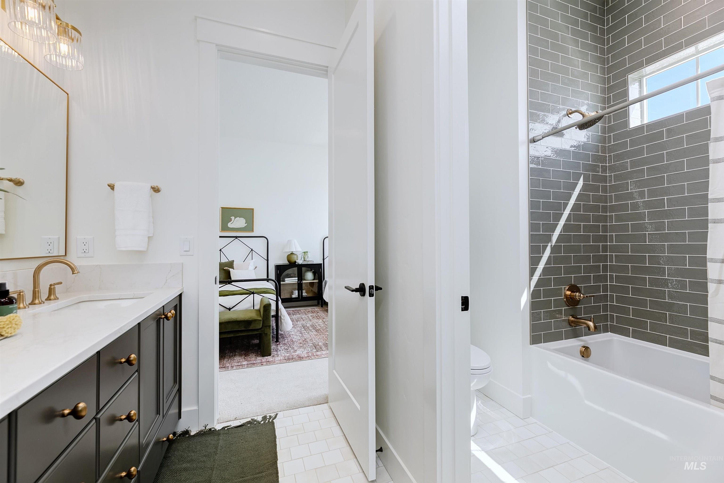 Ensuite bathroom with vanity, shower / bath combo, and light tile patterned floors