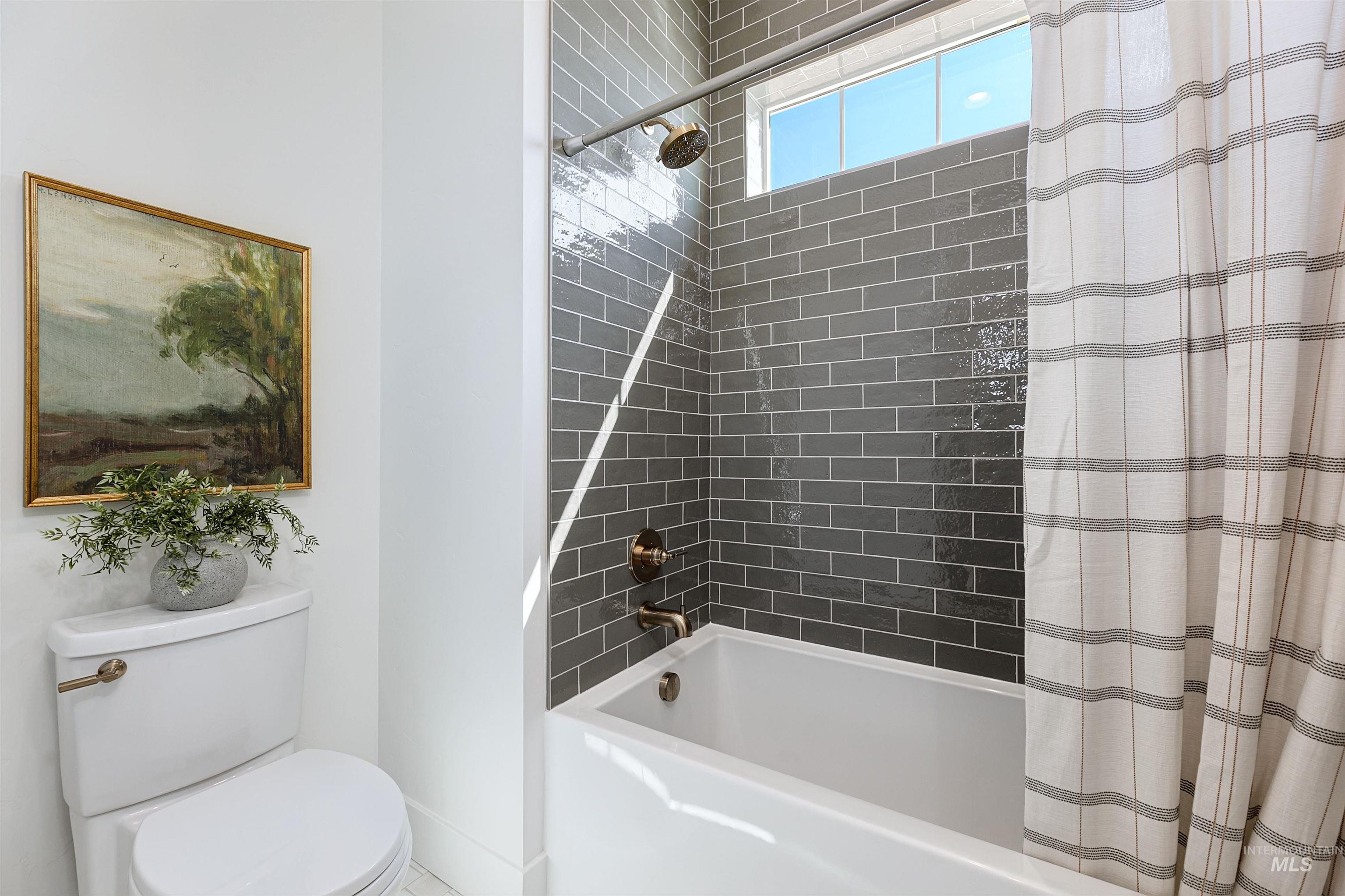 Bathroom featuring shower / bath combination with curtain and toilet