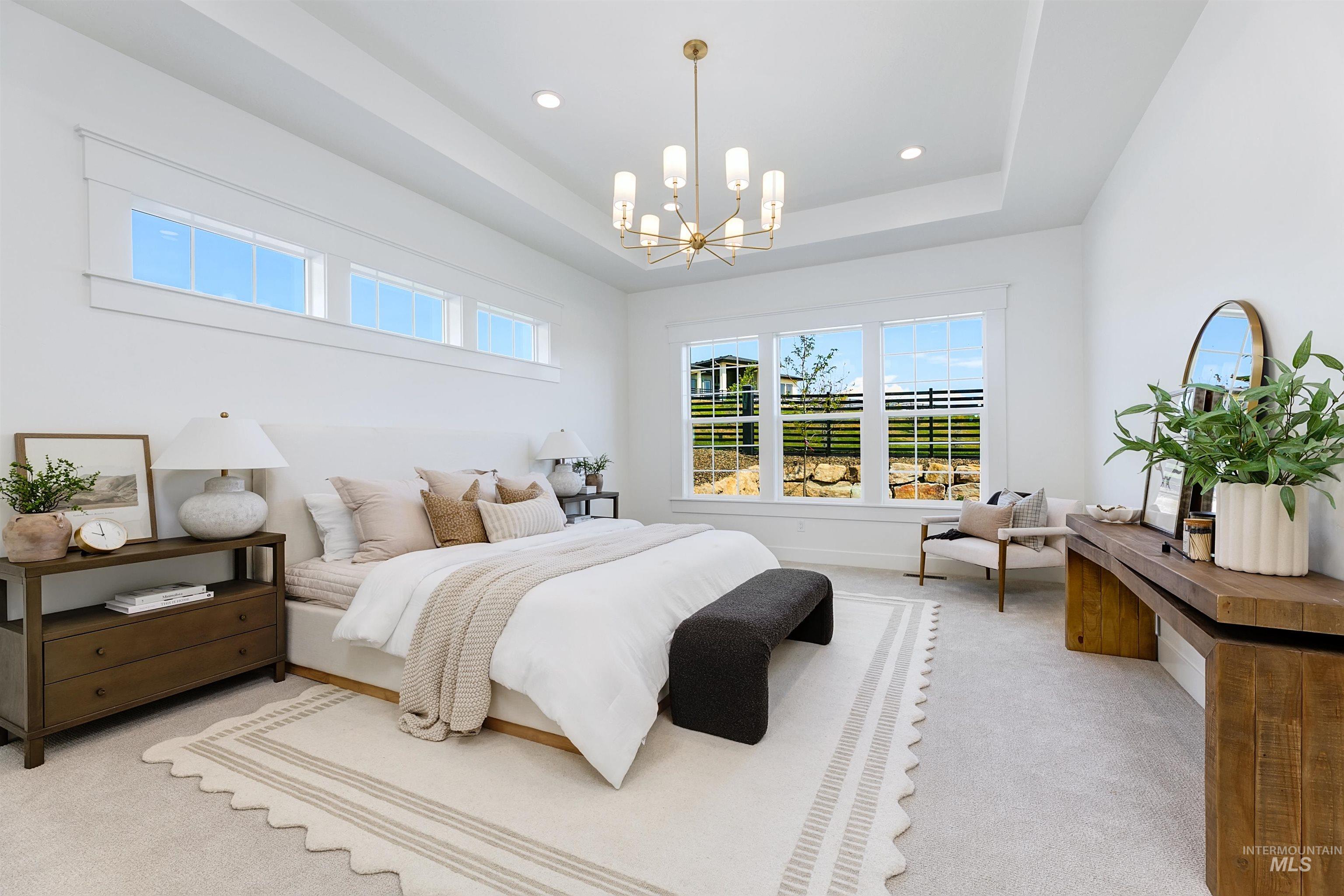 Carpeted bedroom featuring a tray ceiling, a chandelier, and recessed lighting