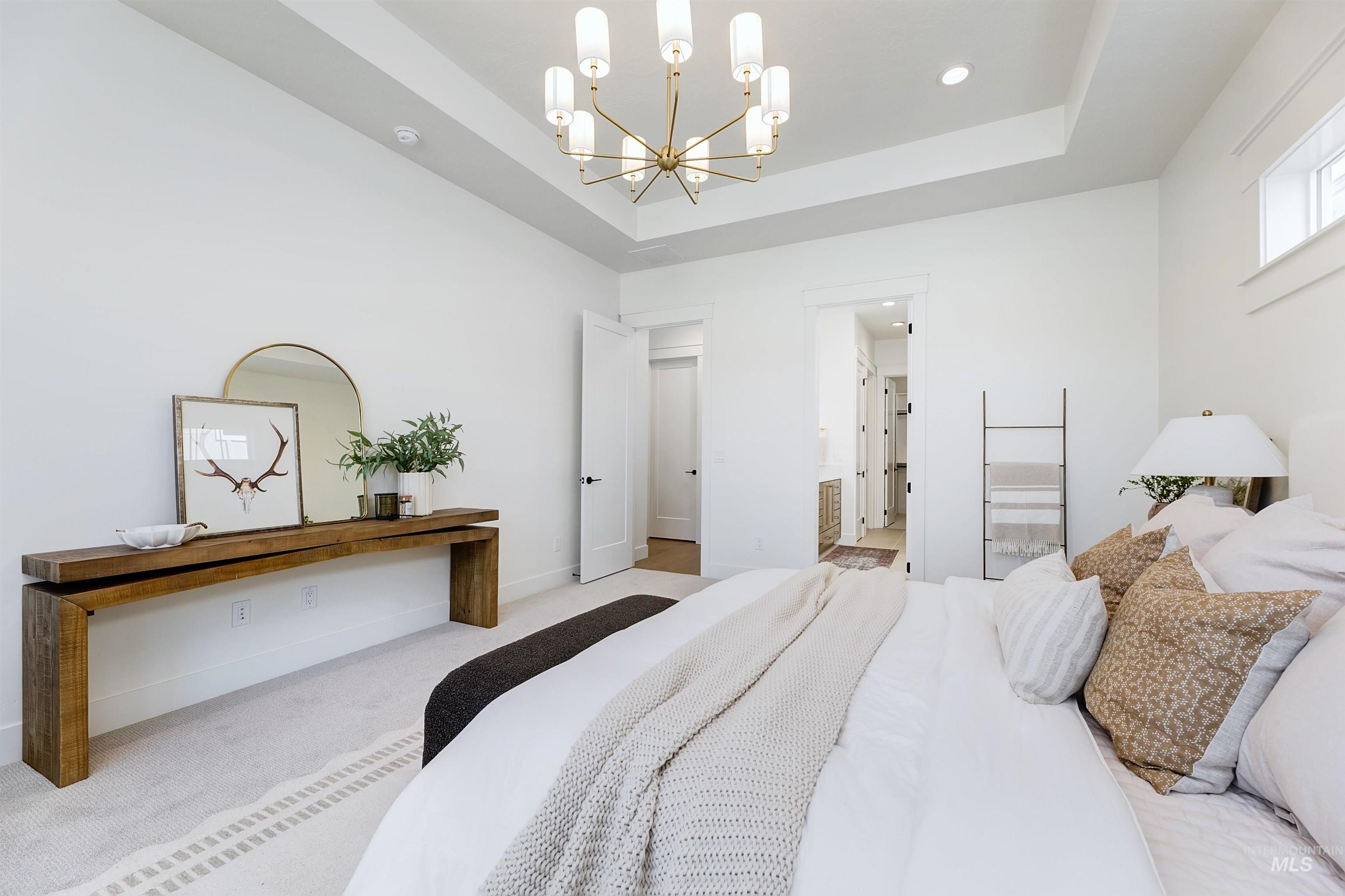 Bedroom with a tray ceiling, a chandelier, carpet flooring, ensuite bath, and recessed lighting