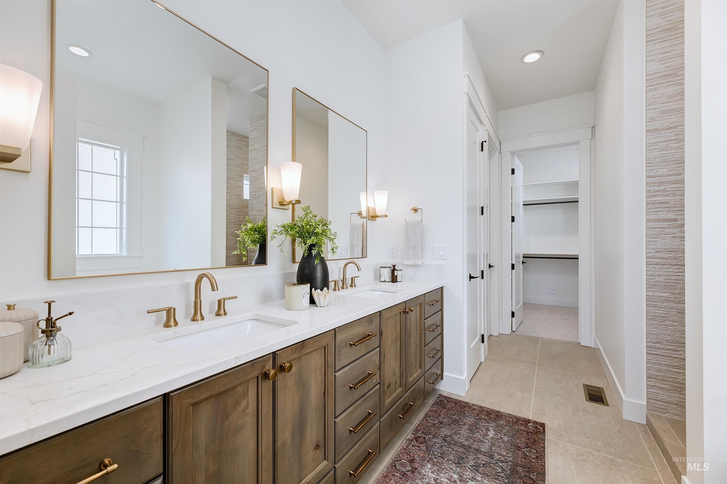 Bathroom with double vanity, light tile patterned floors, a spacious closet, and recessed lighting