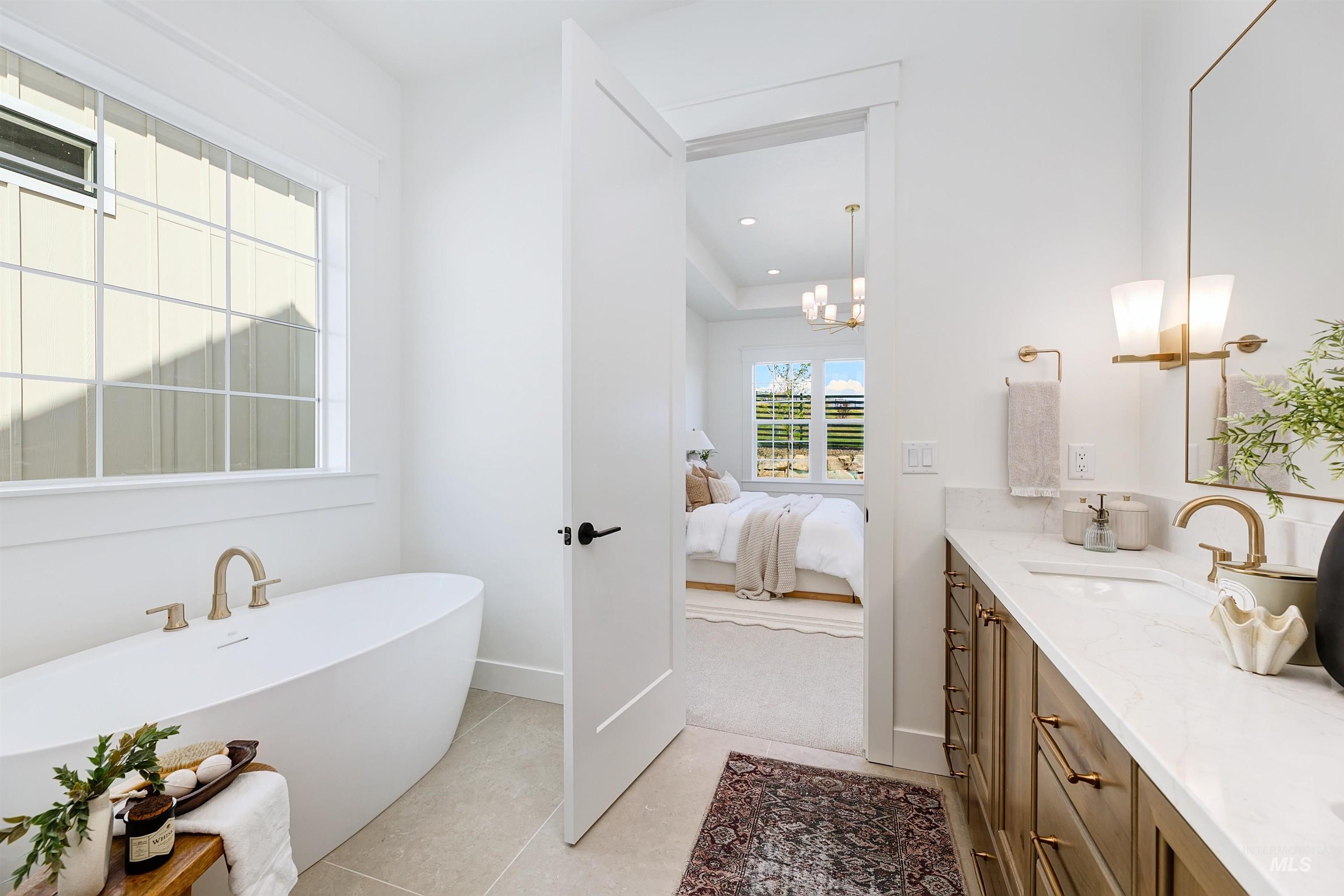 Ensuite bathroom with double vanity, a soaking tub, and light tile patterned flooring