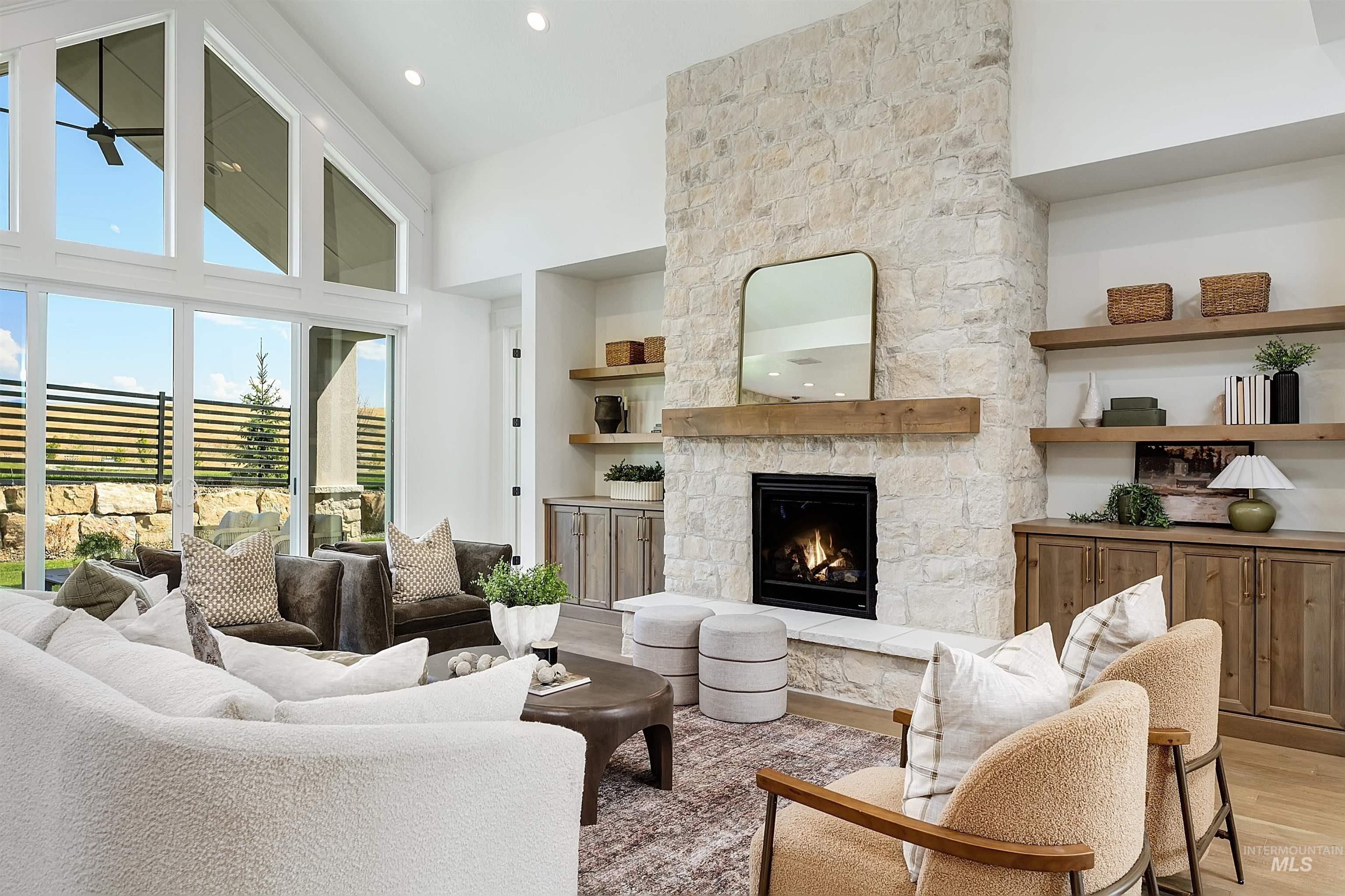 Living room with a high ceiling, a stone fireplace, light wood-type flooring, and recessed lighting