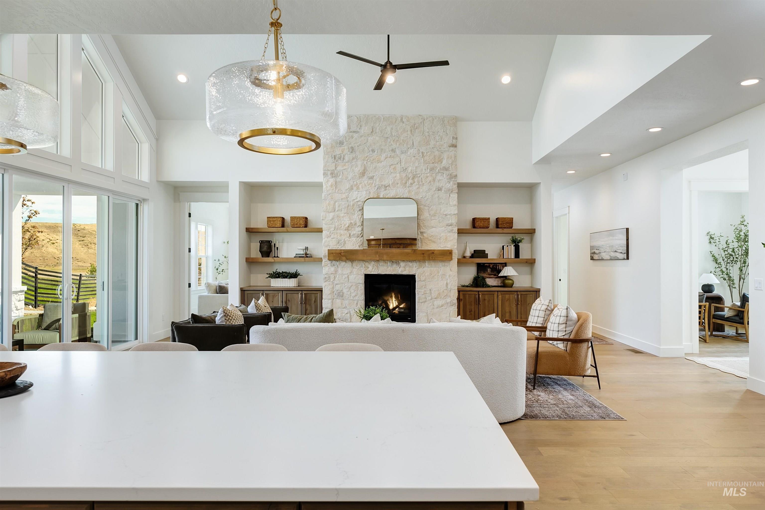 Living area with light wood-type flooring, a fireplace, a high ceiling, recessed lighting, and a ceiling fan